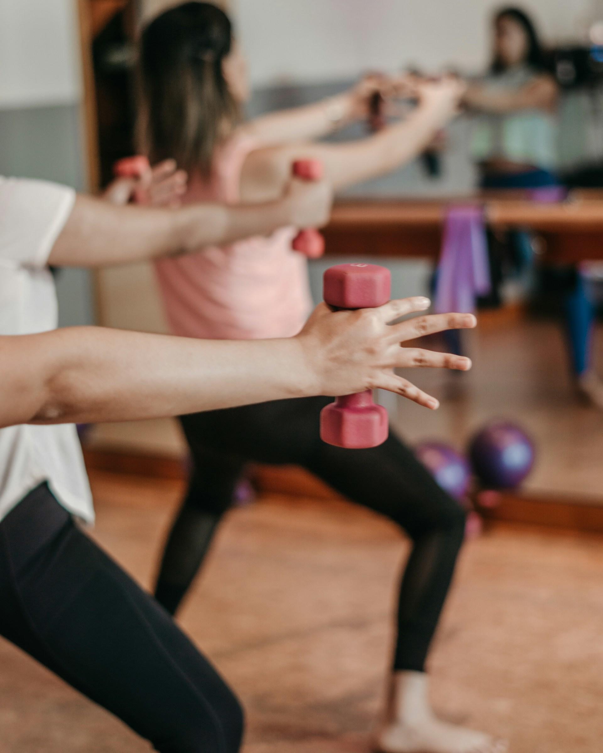 A group exercise class featuring pink dumbbells.