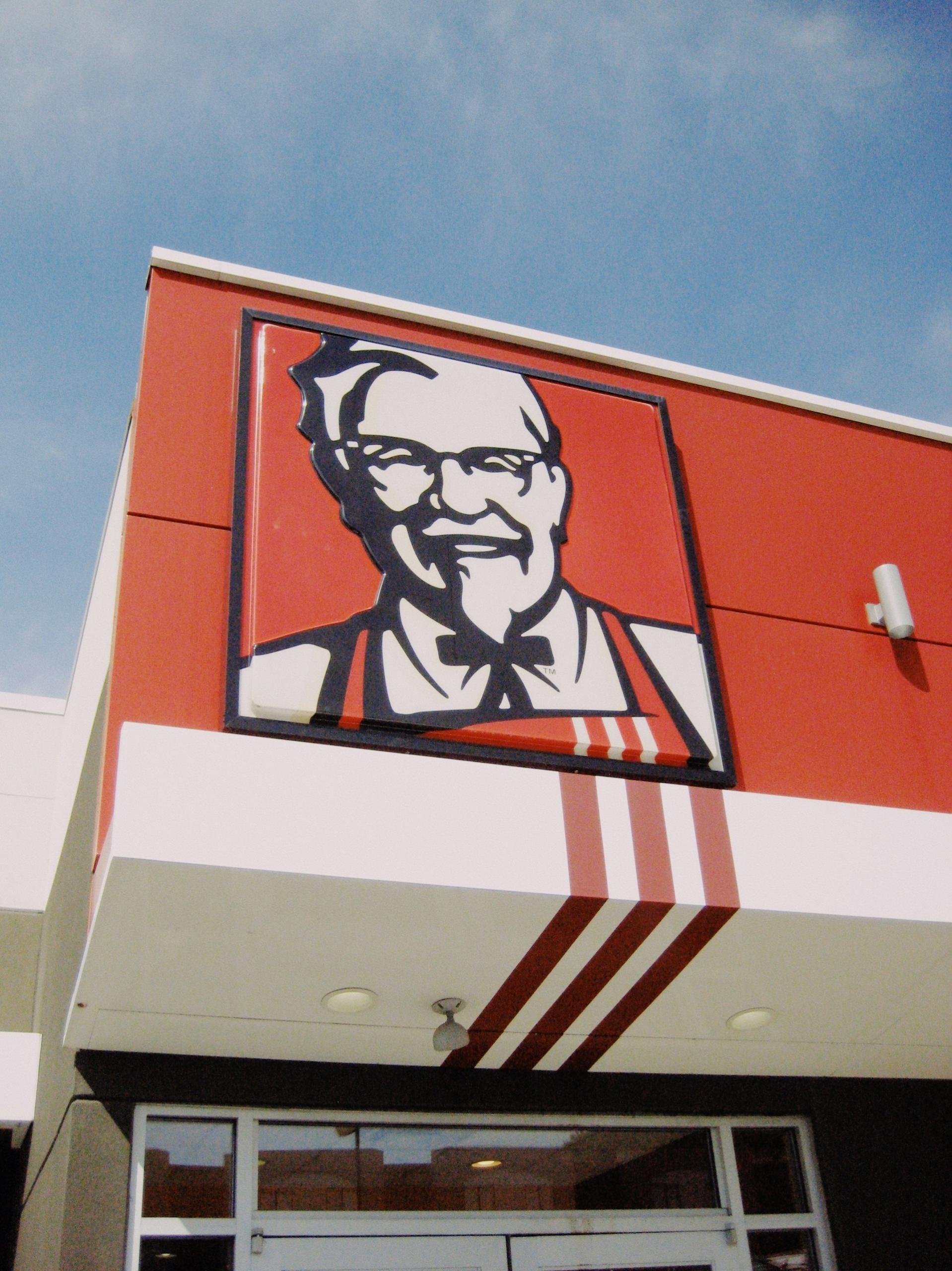 A KFC sign featuring the colonel on a KFC building