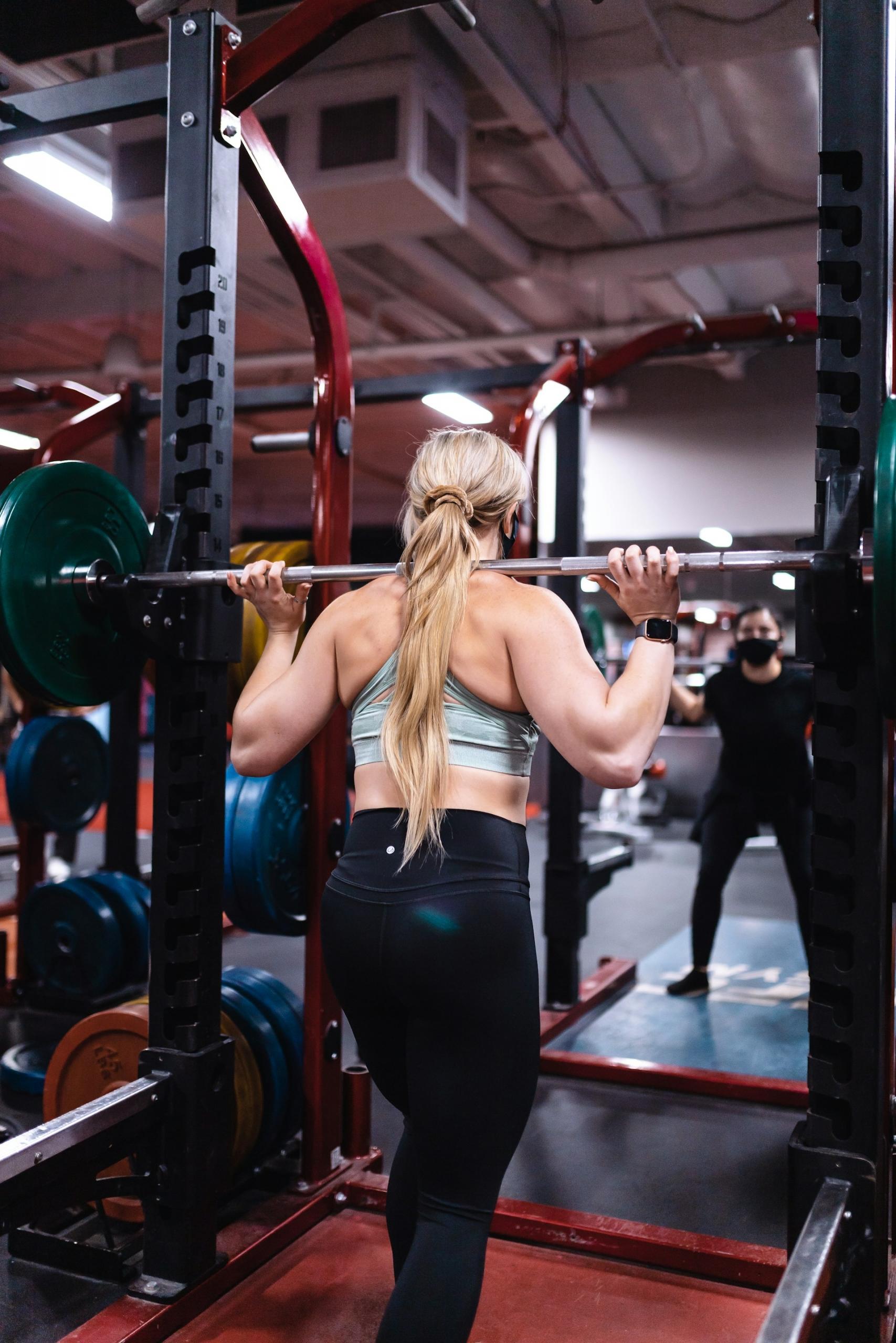 A woman lifts weights in a gym.
