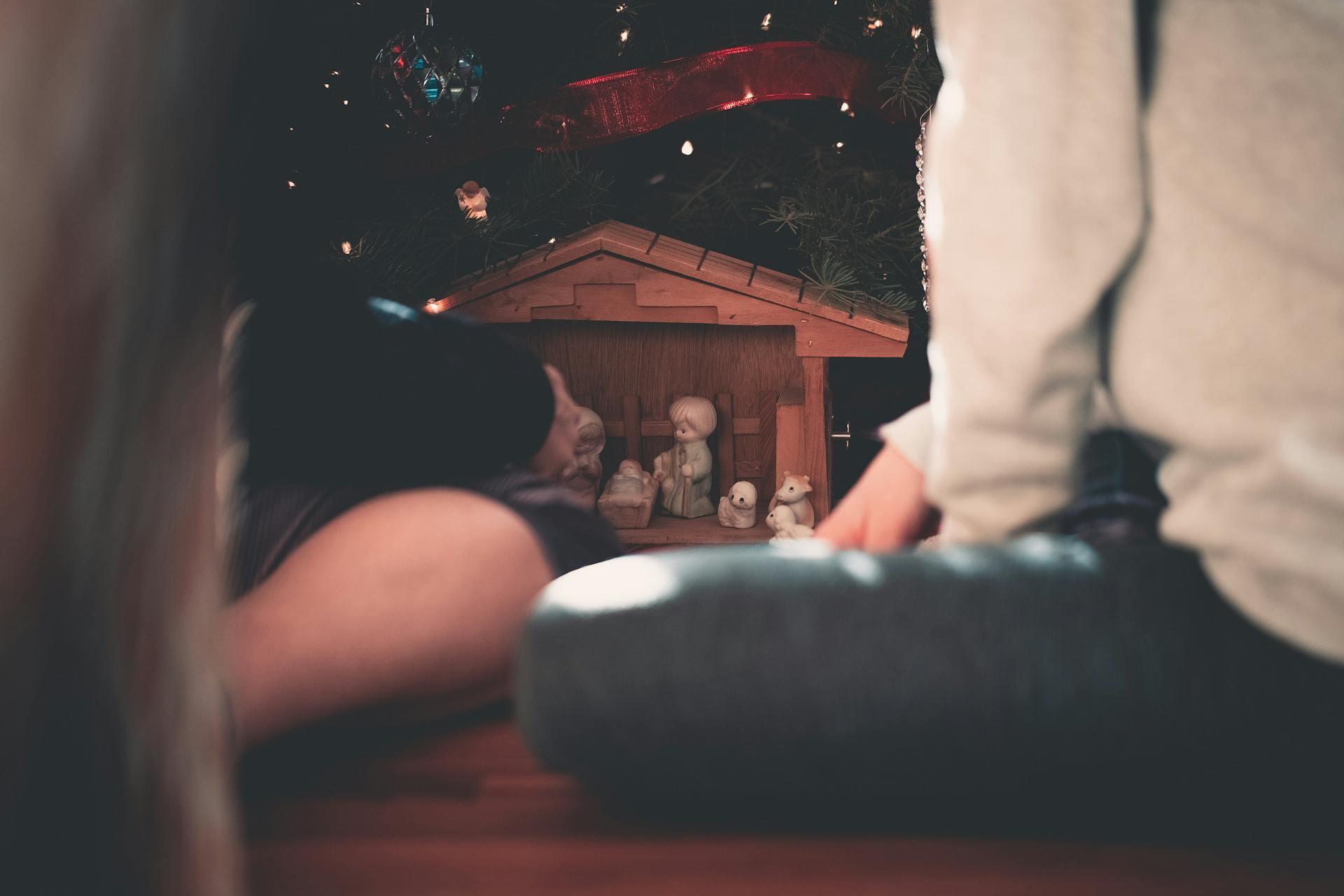 Children look on at a nativity scene made of wood