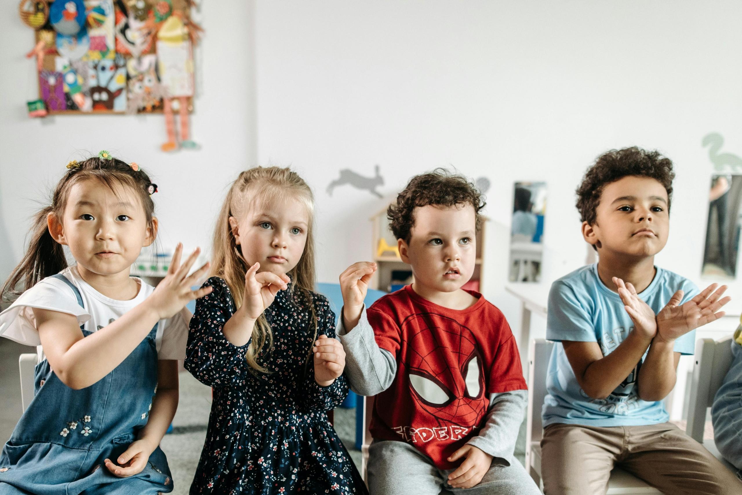 Four kids practicing sign language.