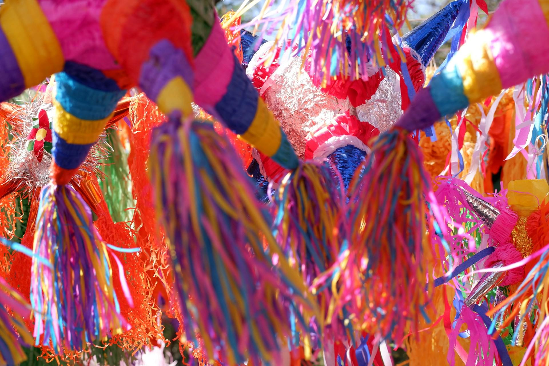 Bright colours of multiple Pinatas hanging in the sky.