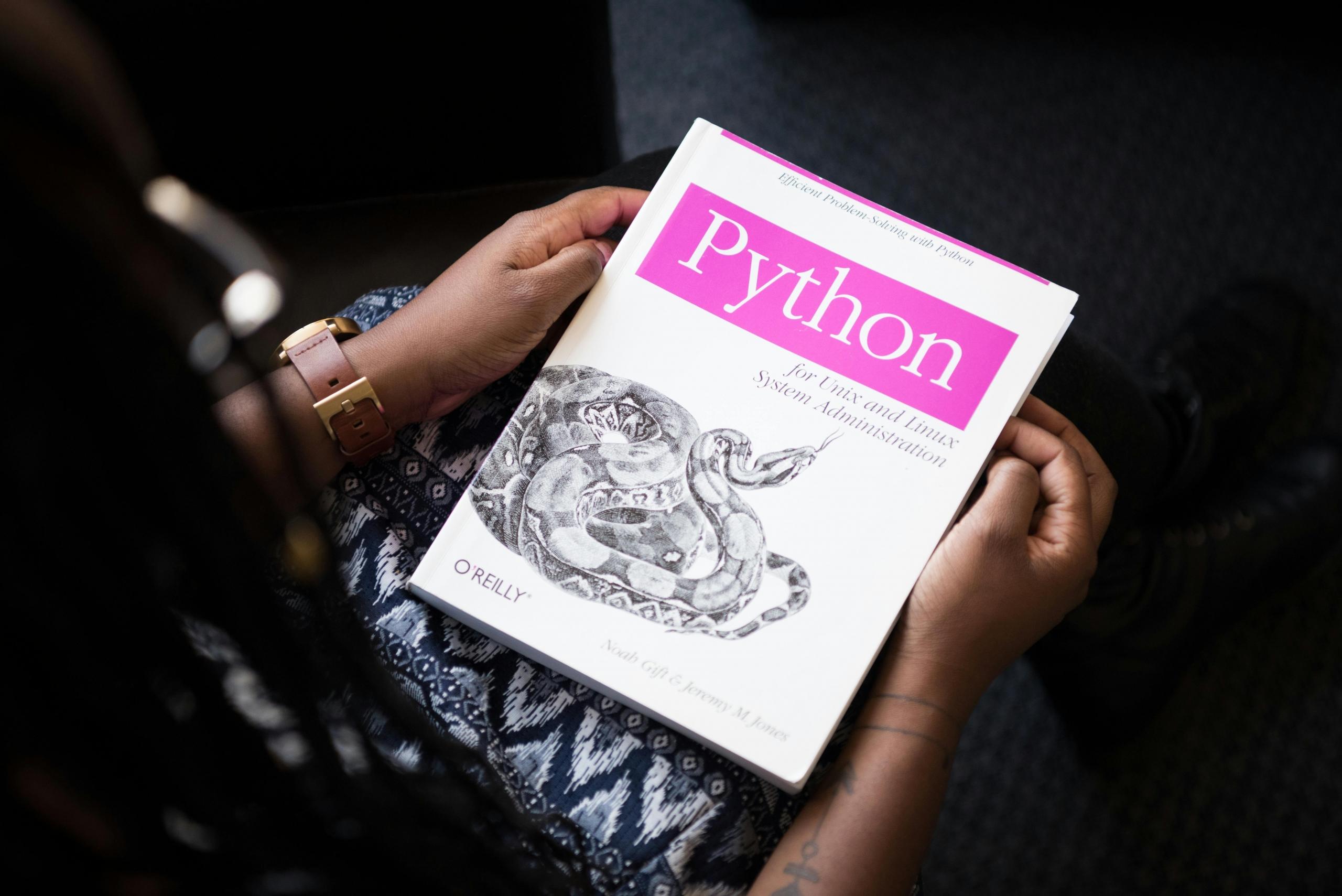A student is holding their Python book in their hands