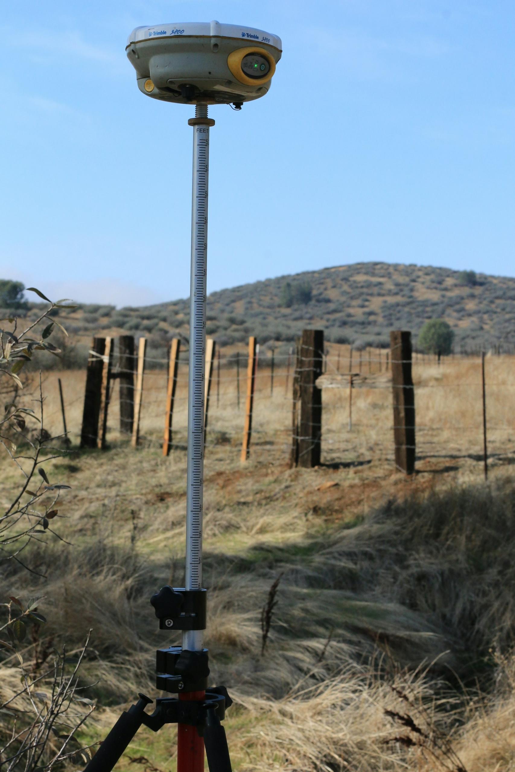 A surveying device in a field on a sunny day.