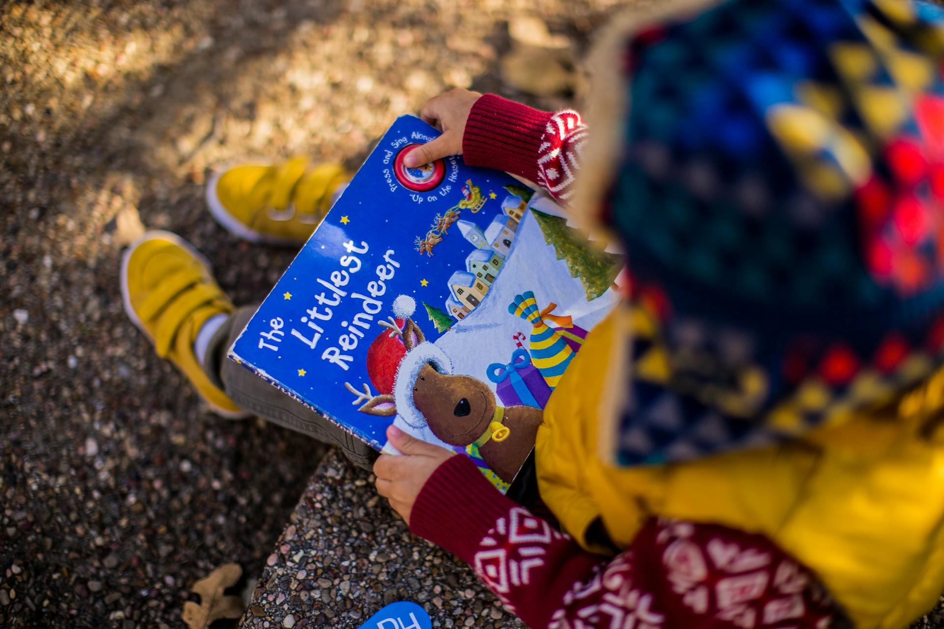 A child reading a book called The Littlest Reindeer