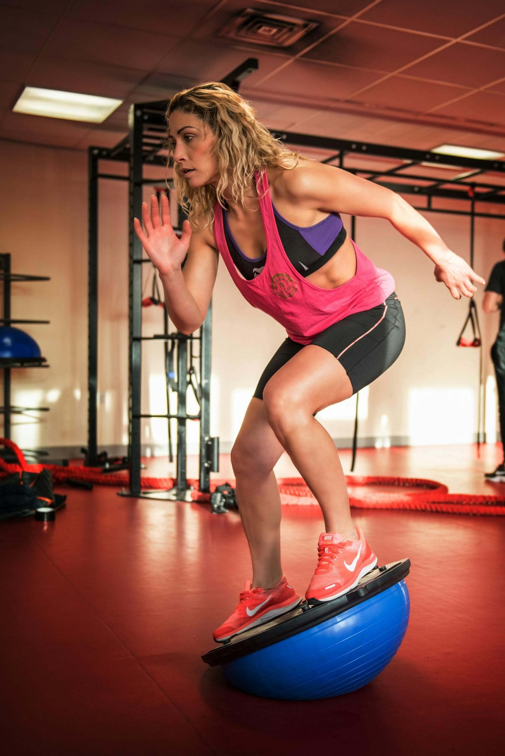 A woman balances on a gym balance ball.