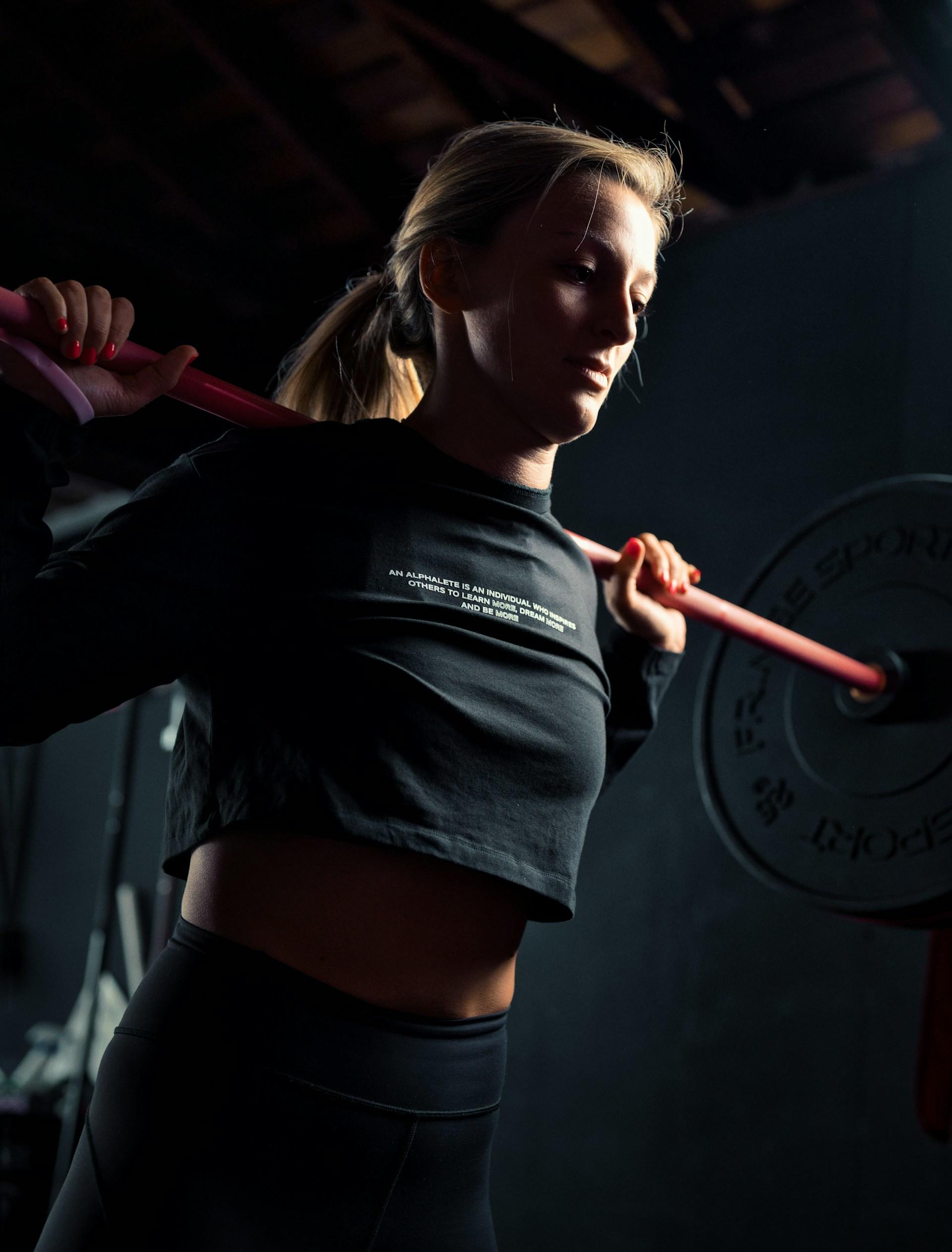 A woman wearing black lifts a barbell. 