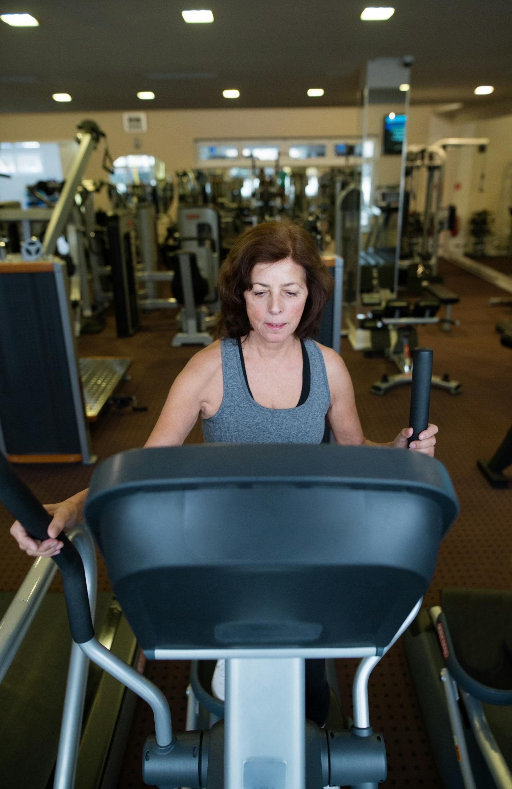 A woman in a gym on a cardio machine.