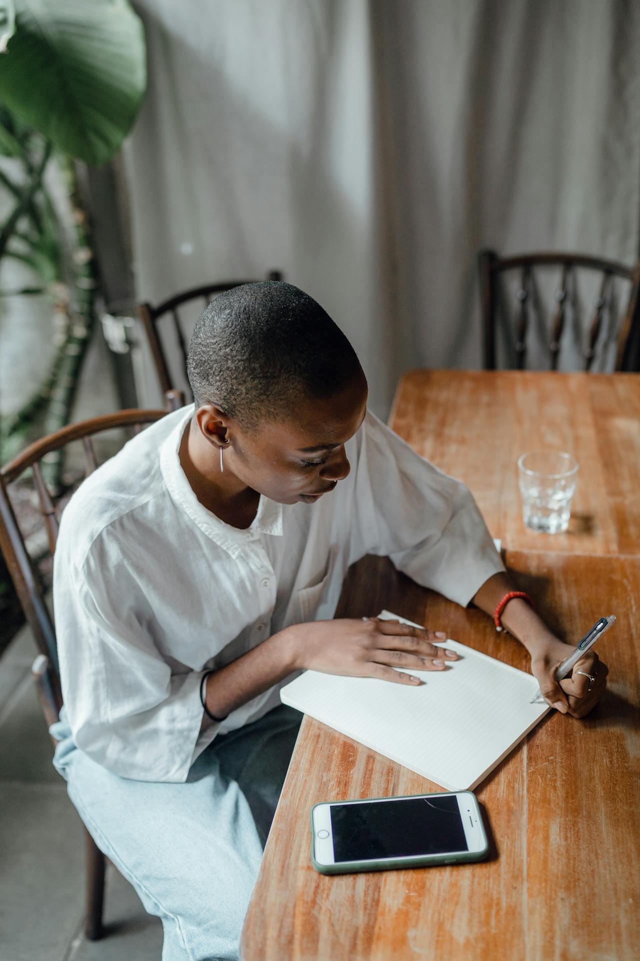 A woman sits at a table writing a letter