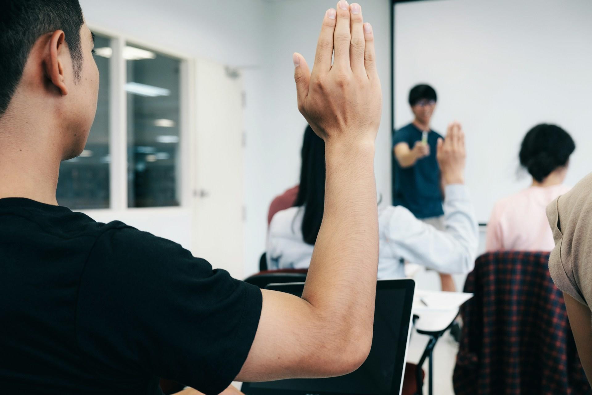 Students raise their hands in class.