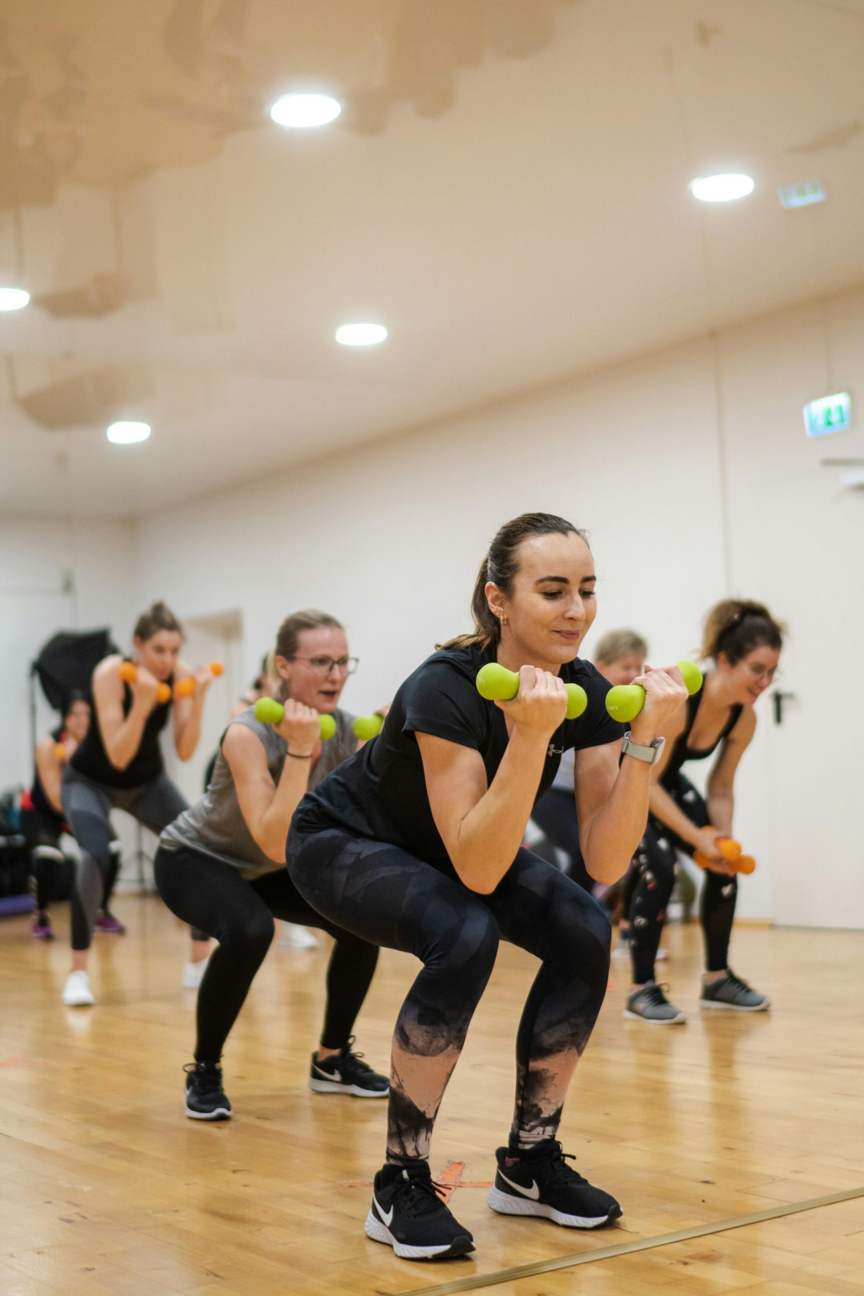 A group of women working out in a studio with green dumbbells.