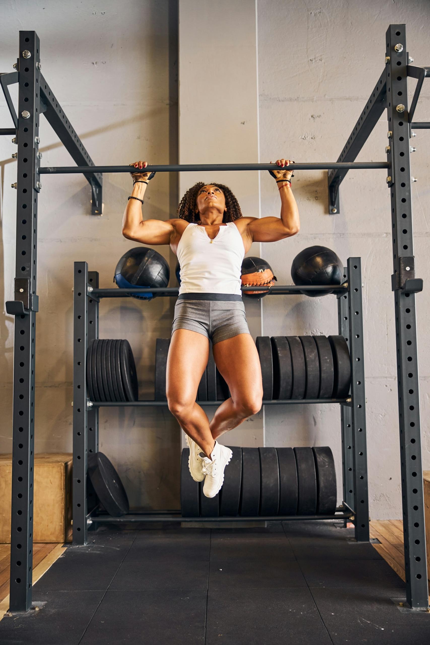 A woman in gym clothing does a pull-up.