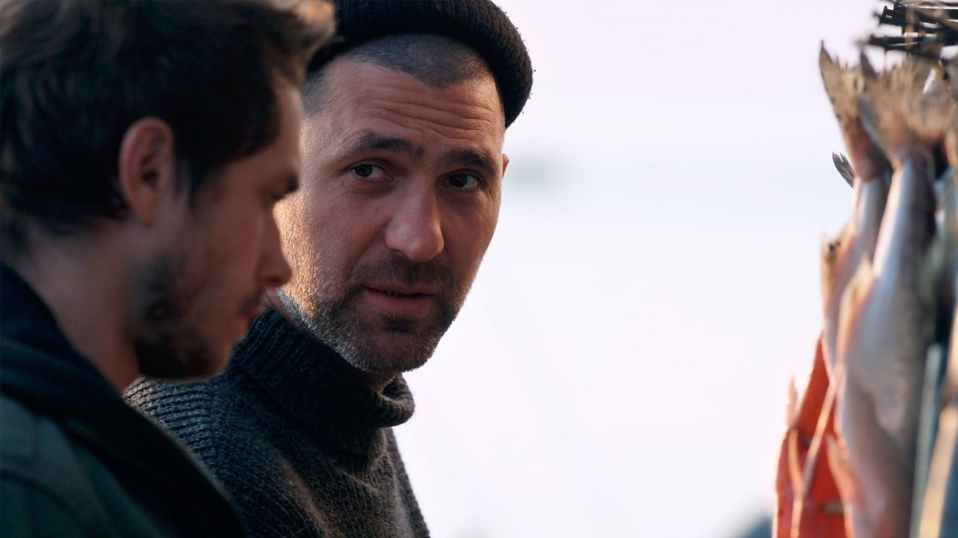 an older man looking at a younger man during a conversation. 