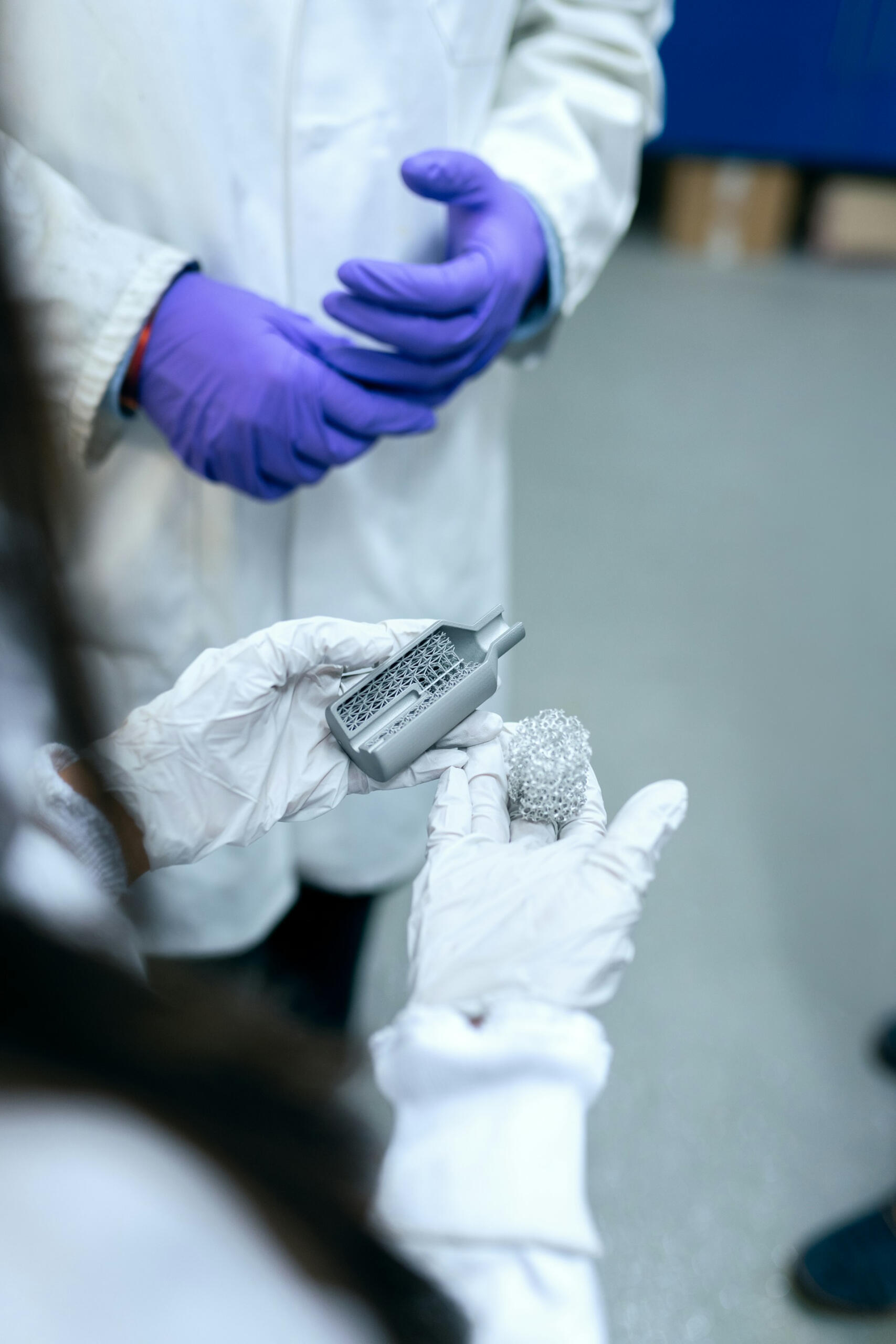 Engineers wearing lab coats and gloves look at an item.
