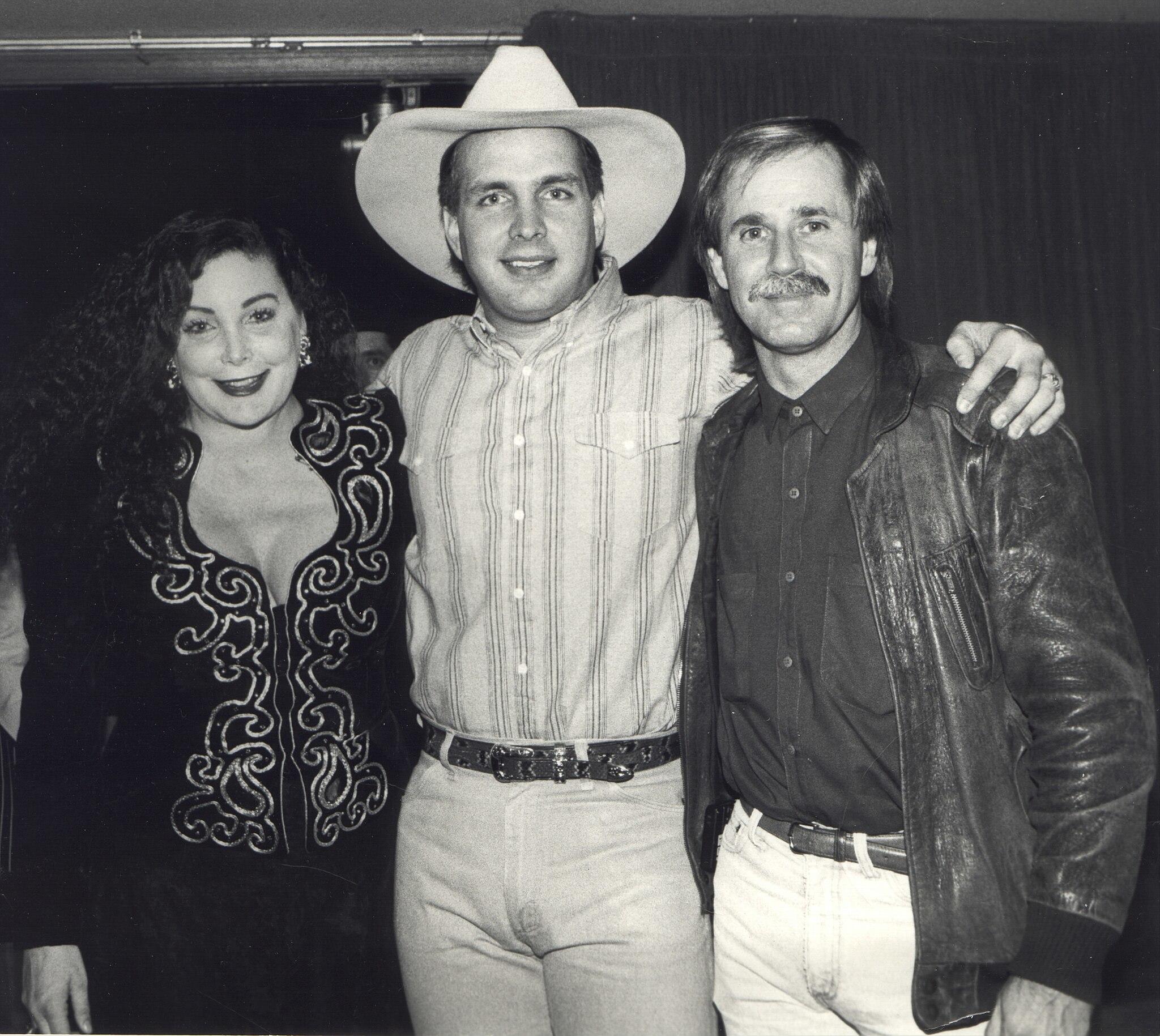 black and white photo of Garth Brooks with two attendees beside him