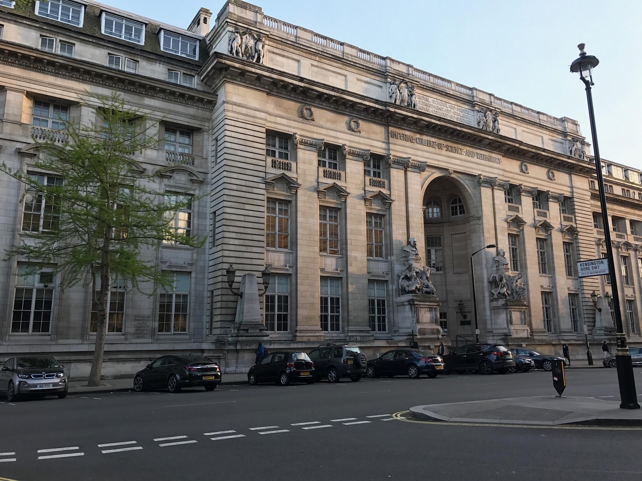 A stone building with cars parked in front during daytime.