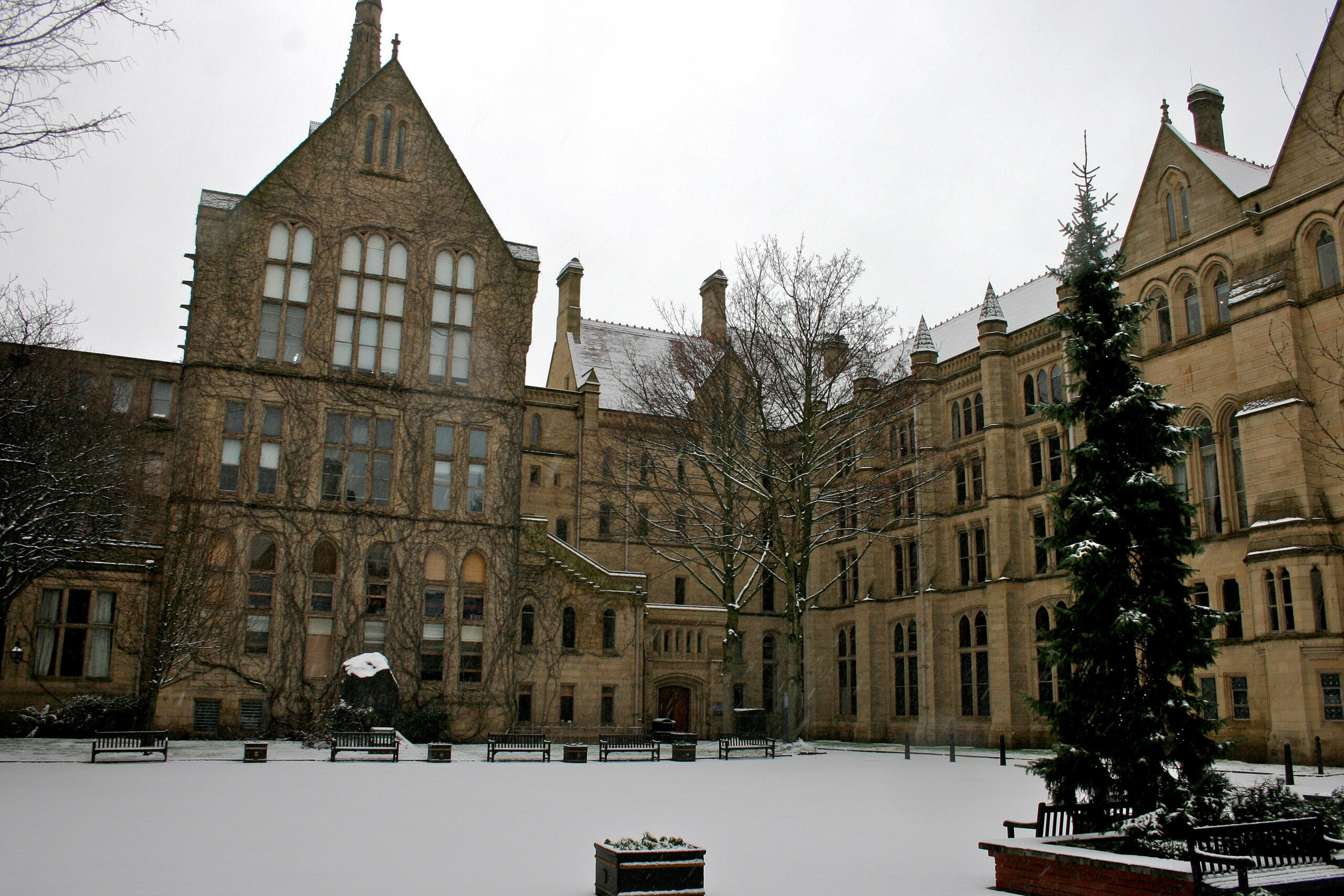 A stone building on a cloudy day with snow on the ground.
