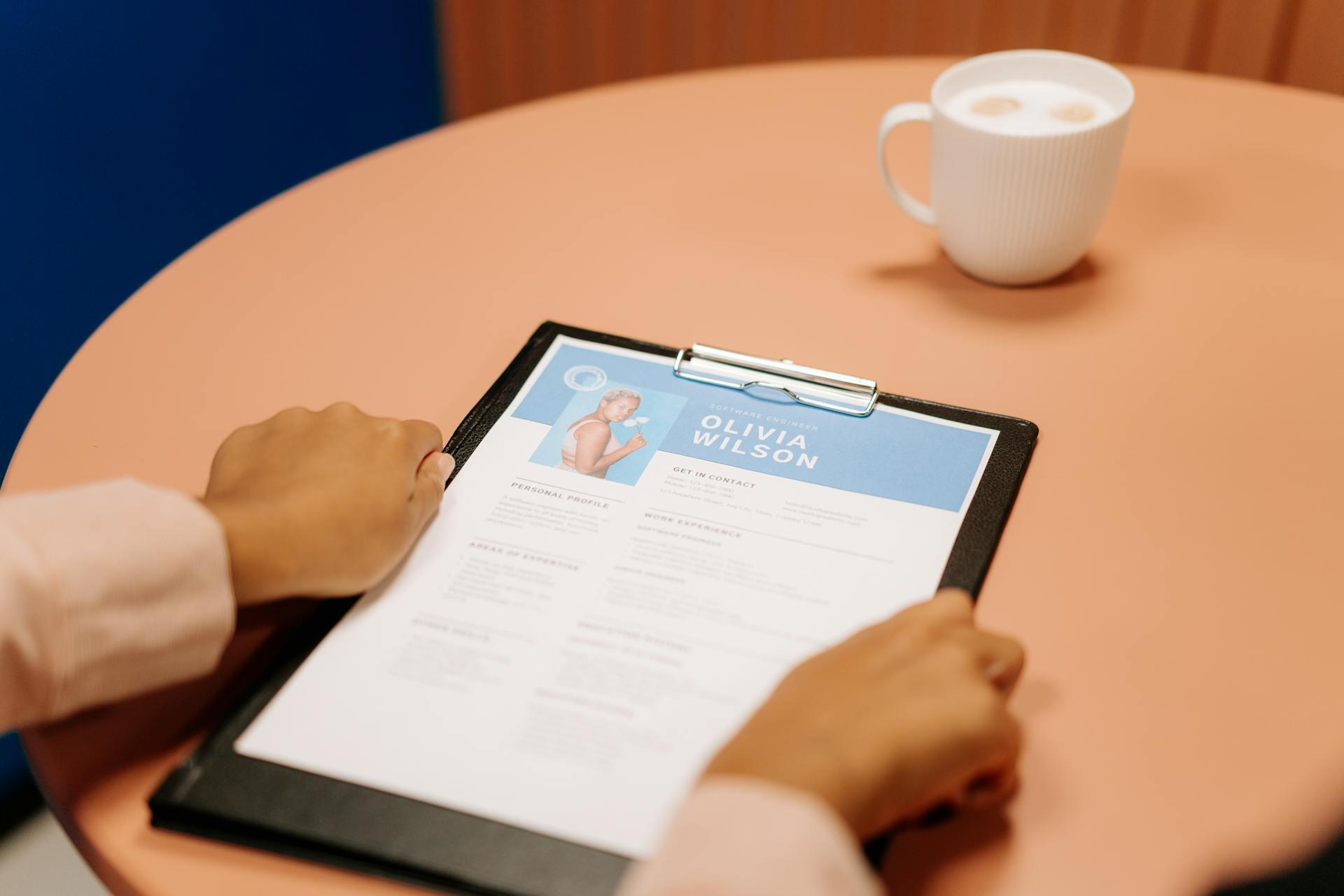 A person reads a resume on a table