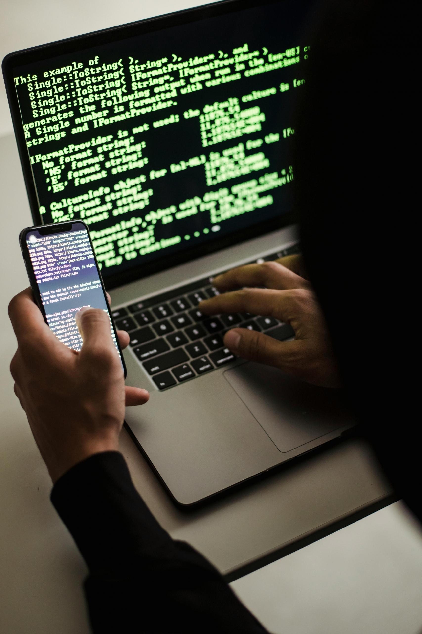 smartphone-typing-on-laptop-with-code-at-desk