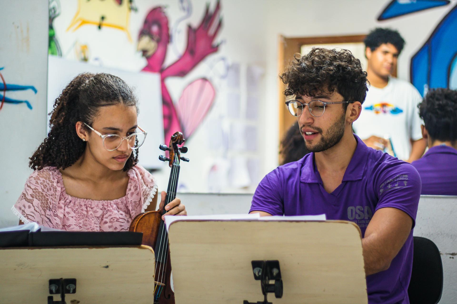 A teacher and student of the violin working together behind sheet music.
