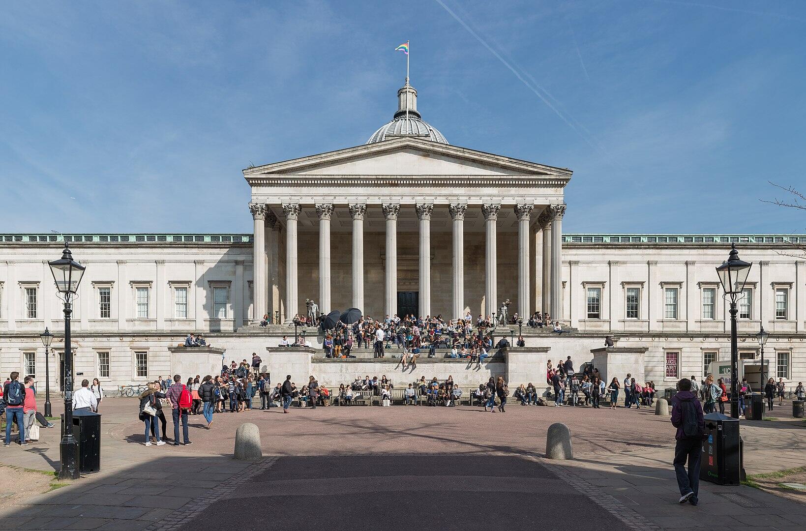 A stone building with people in front of it on a sunny day.