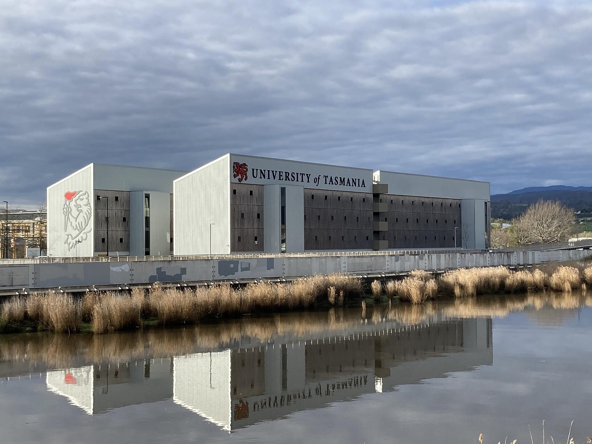 Two white buildings next to a body of water on a cloudy day.