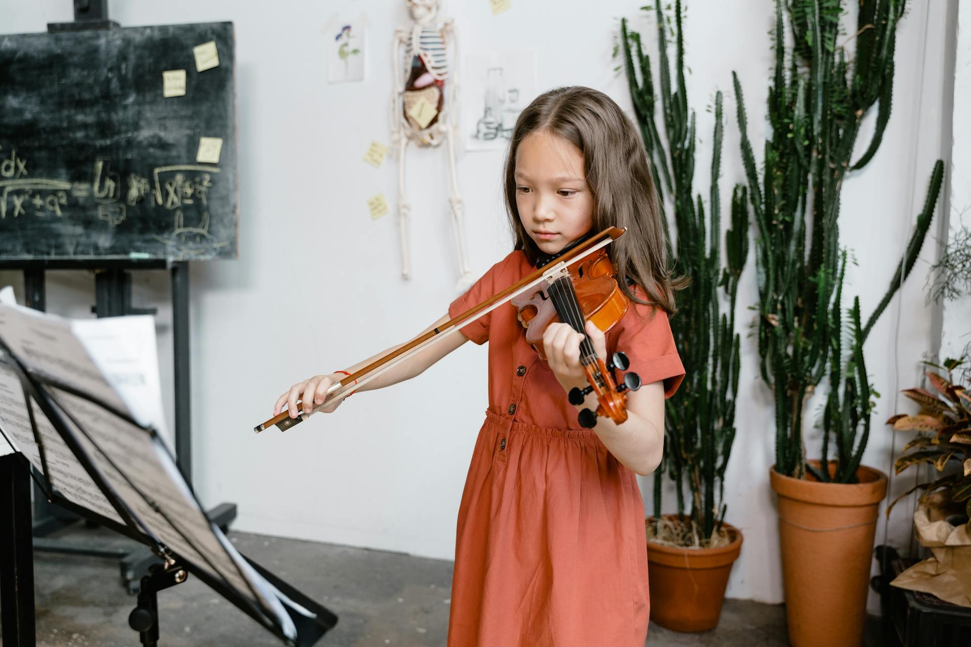 Young girl practising violin in front of sheet music