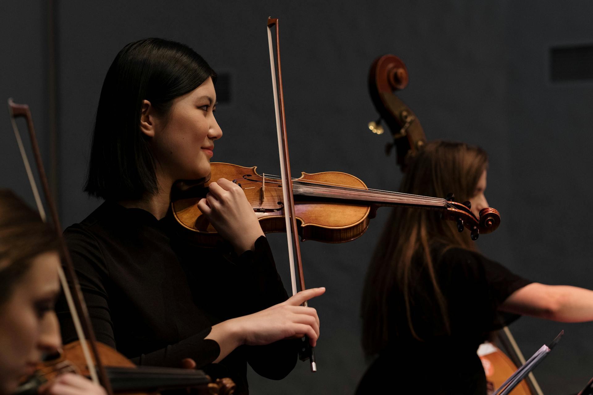 A woman performs on the violin as part of an ensemble.