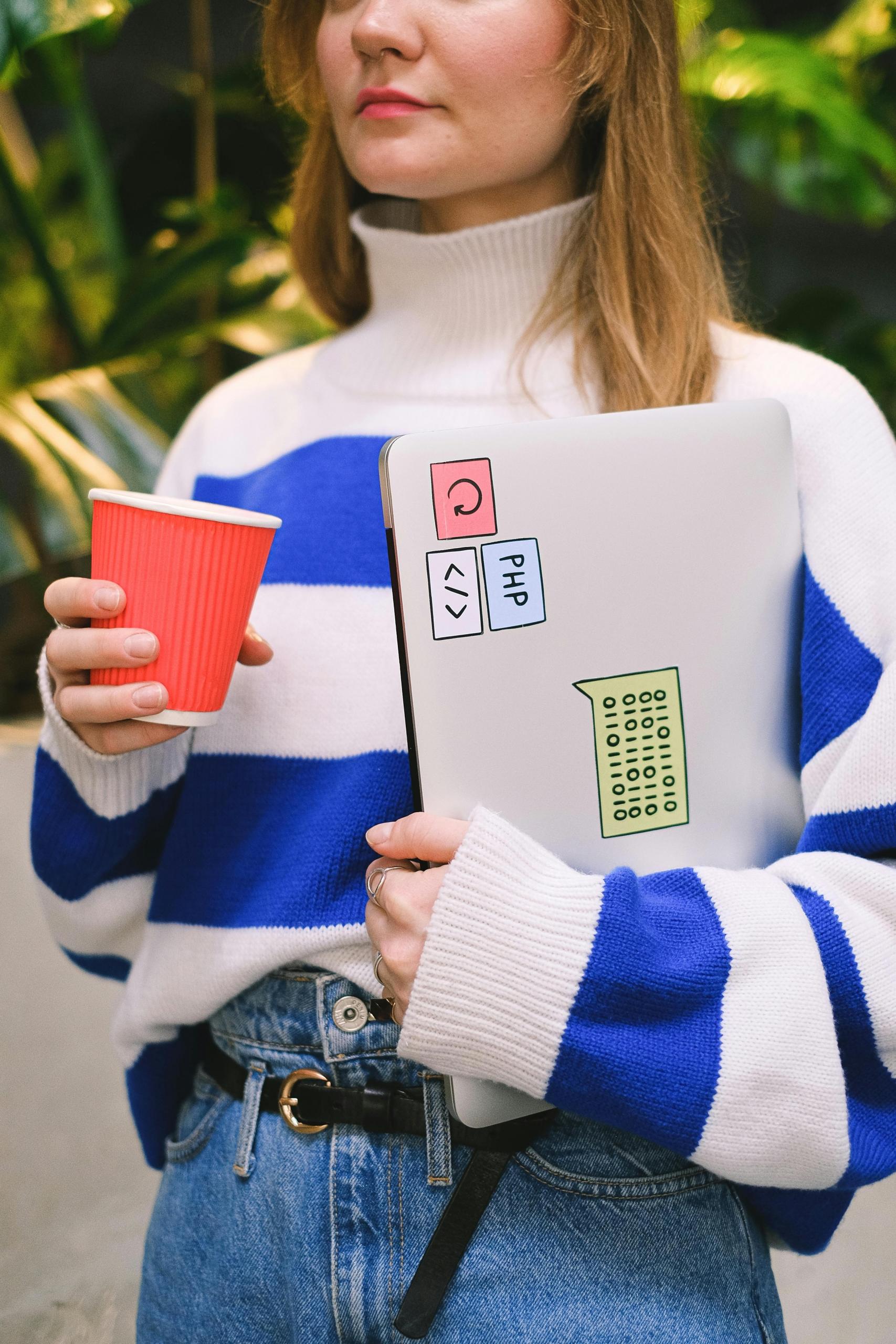 A young programming student holding her laptop