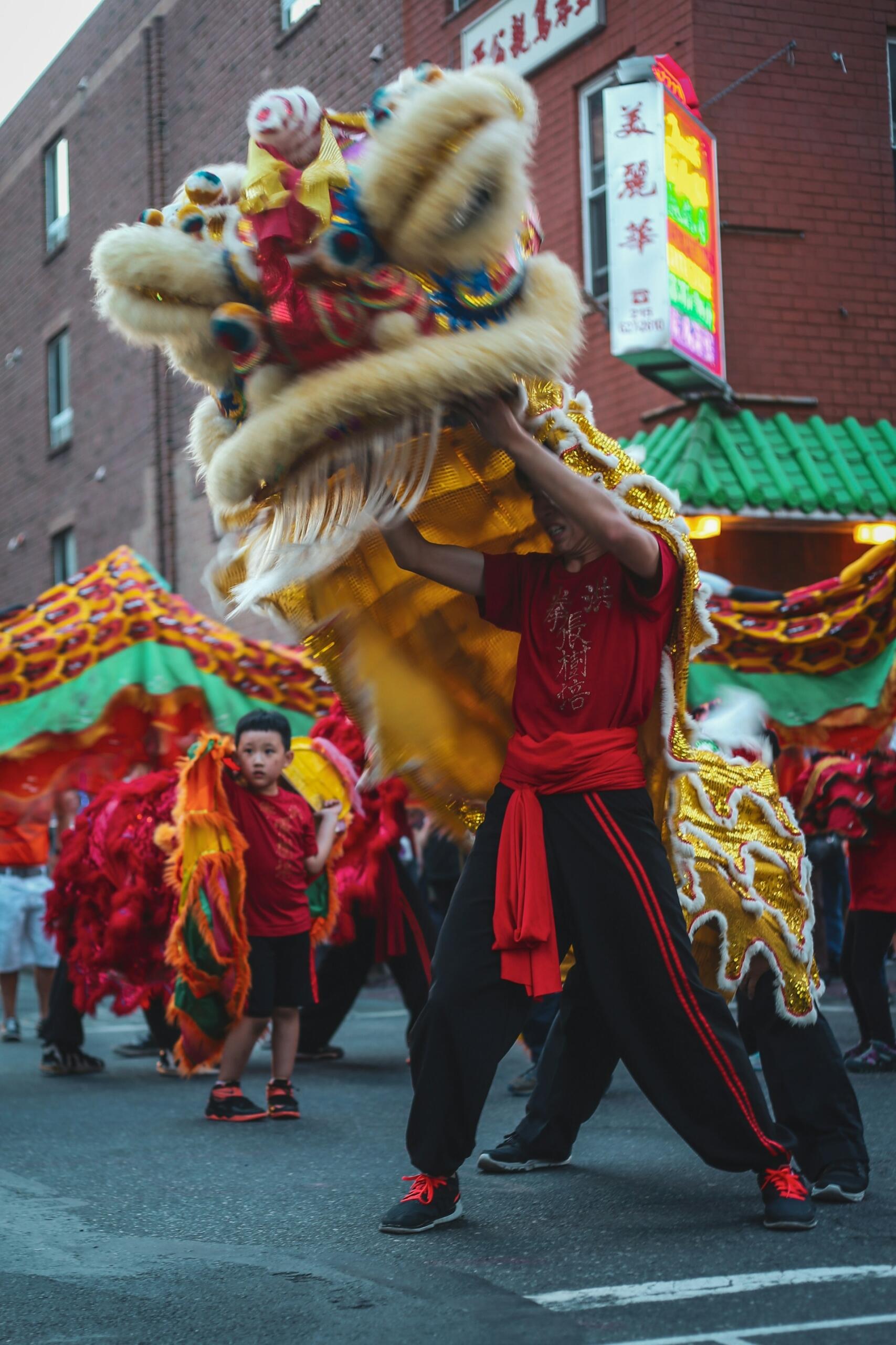 A man wearing red holds up a puppet dragon head.