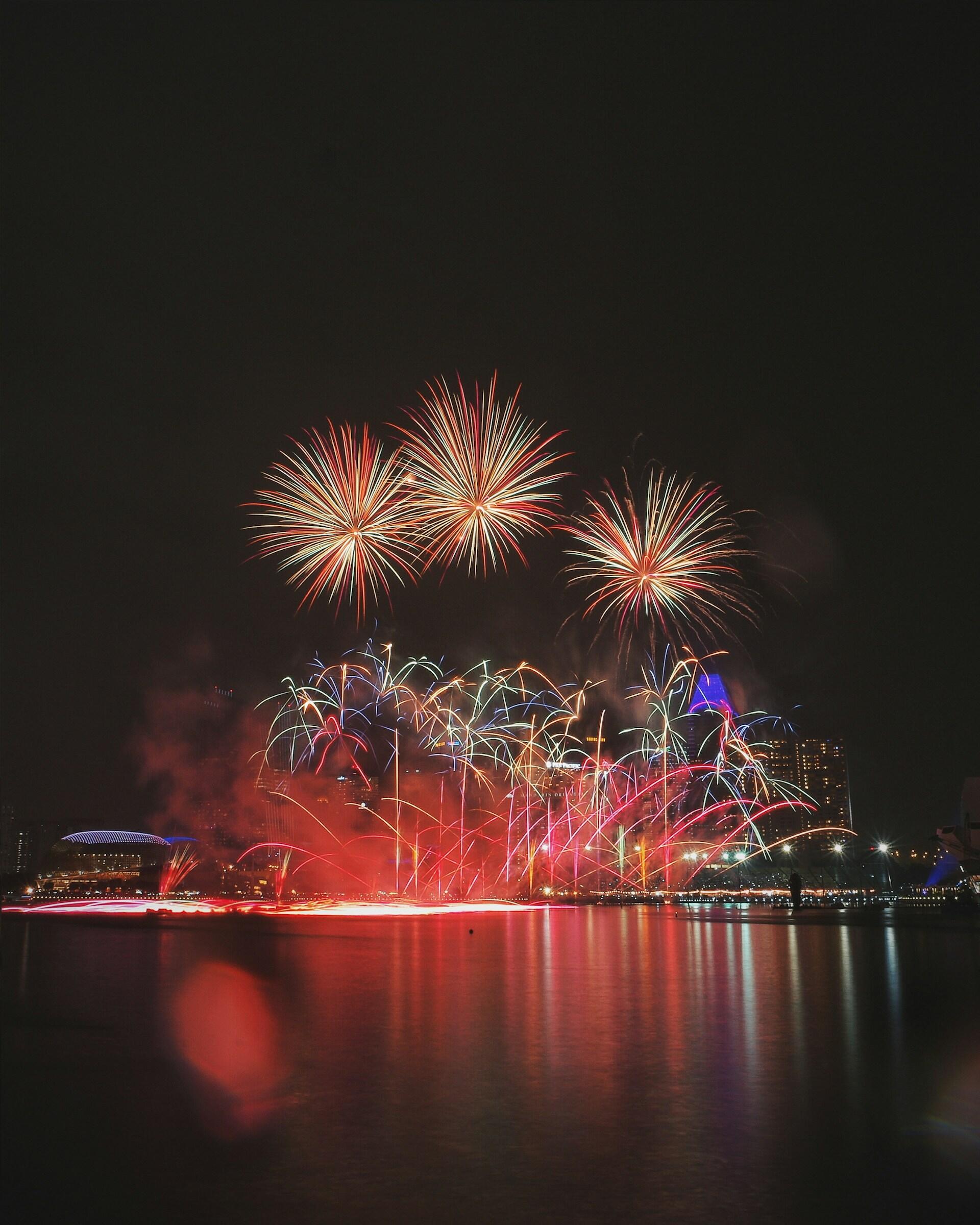 Three bursts of fireworks over water at night.