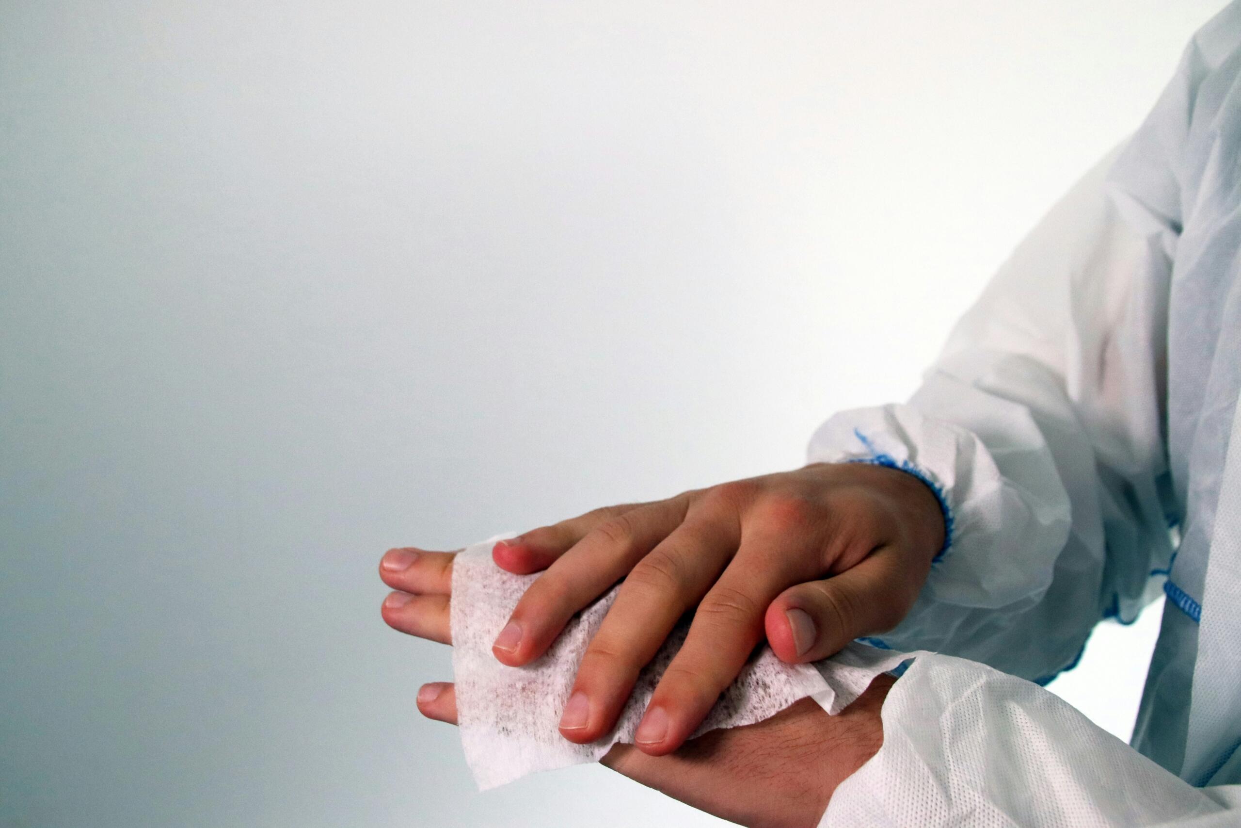 Person in a lab coat wiping hands with a paper towel.