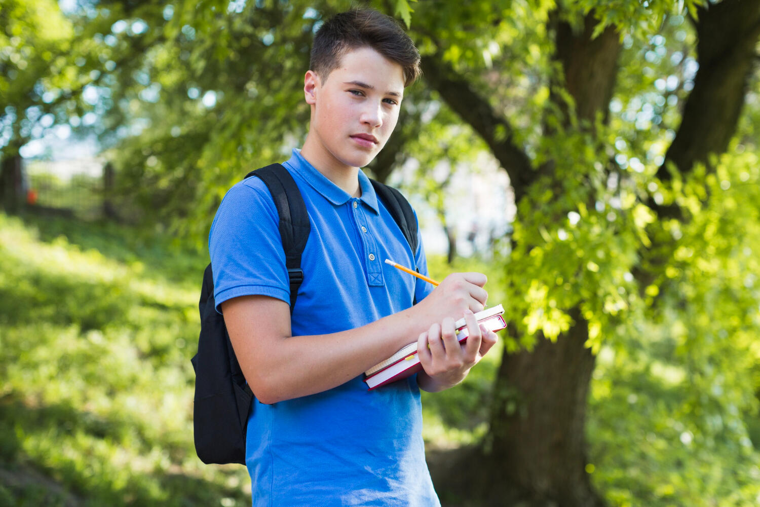 a male student wearing a bag and holding books