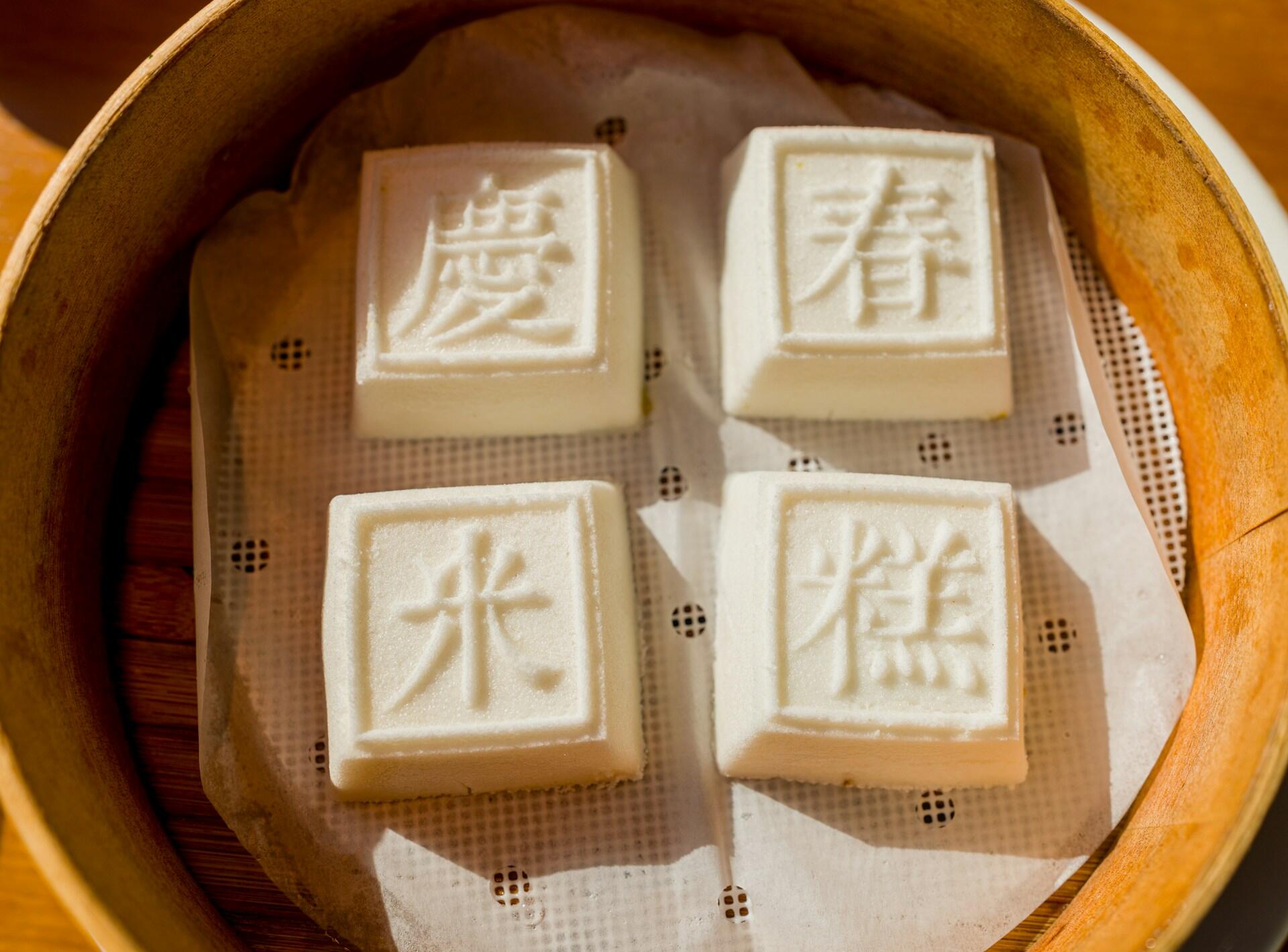 Four white cakes in a wicker steam basket.