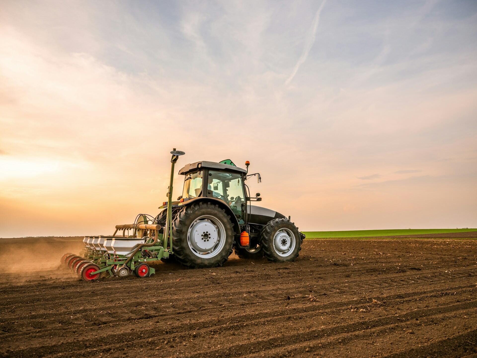 A tractor in a field at sunrise.