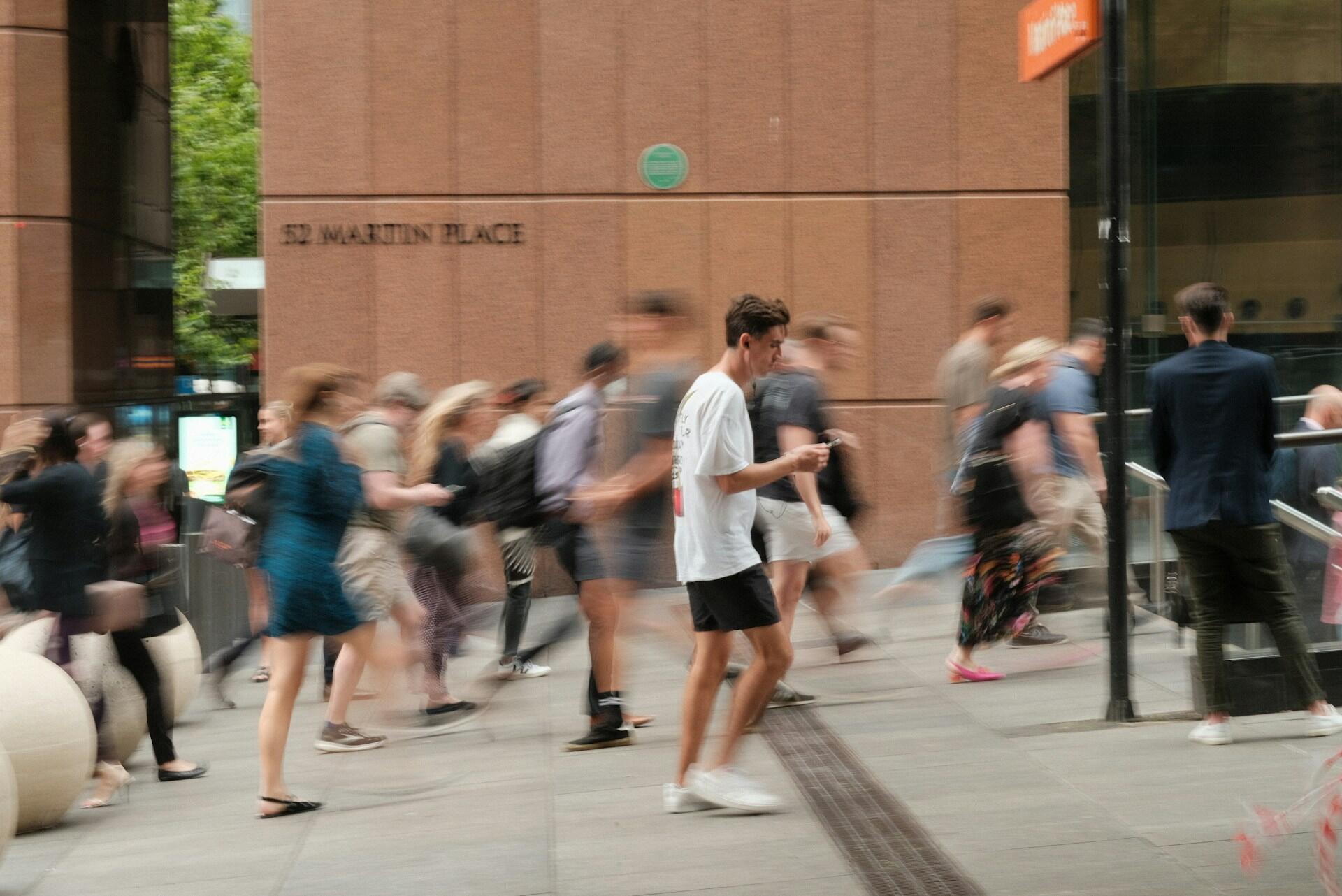 Blurred motion image of people walking on a city sidewalk near 52 Martin Place building.