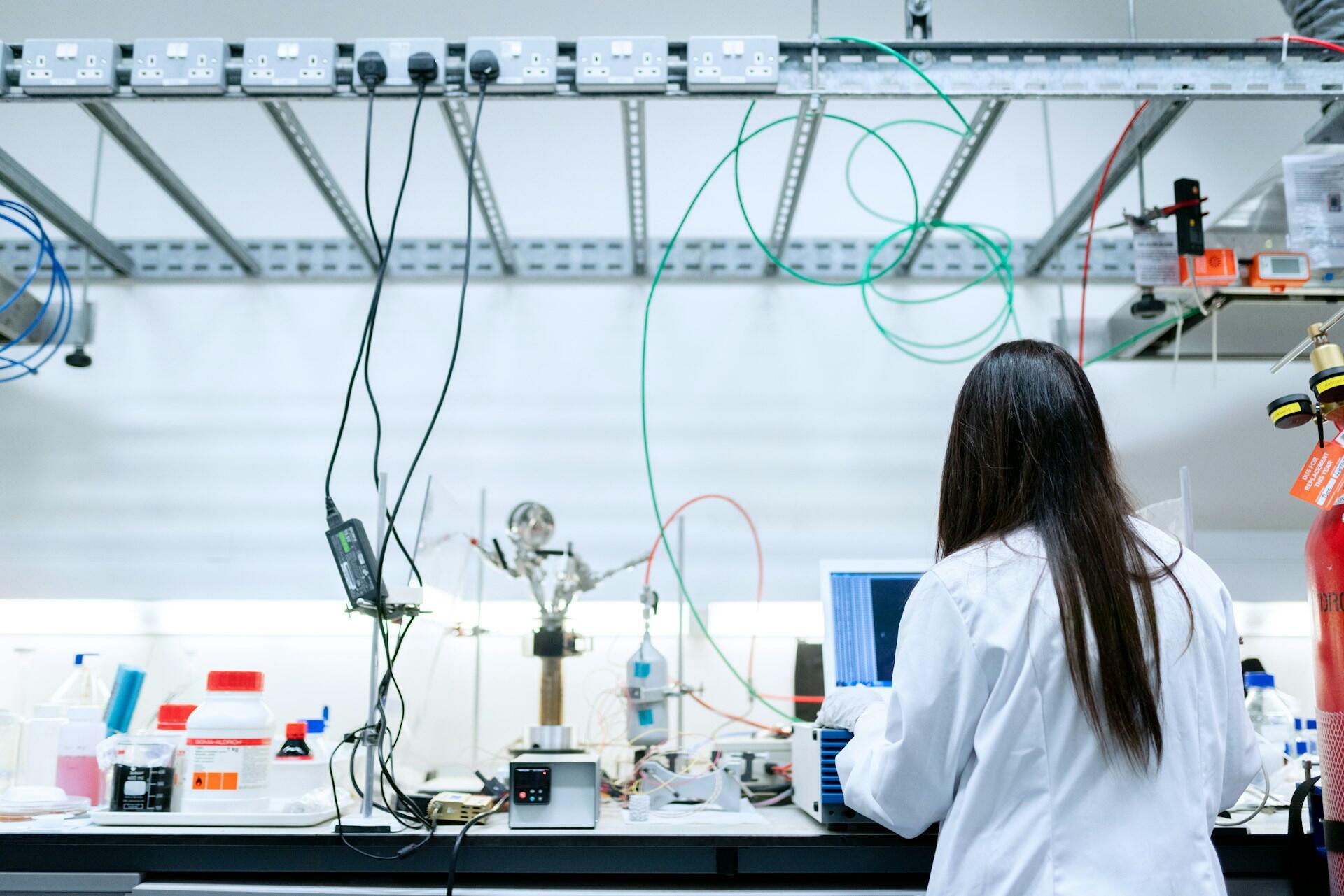 A person in a white lab coat working in a lab. 