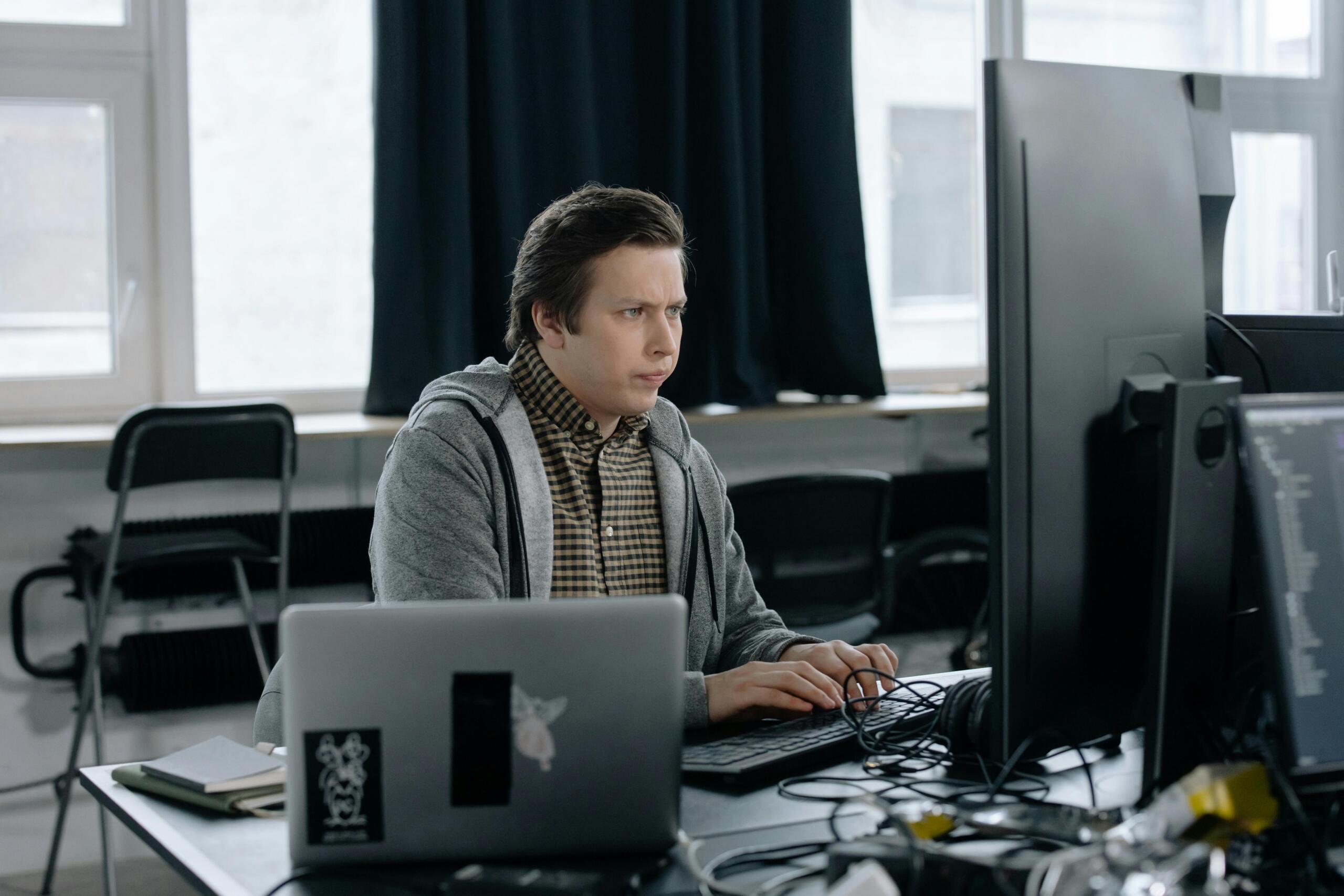 A man programming on his laptop, with lines of code visible on the screen.