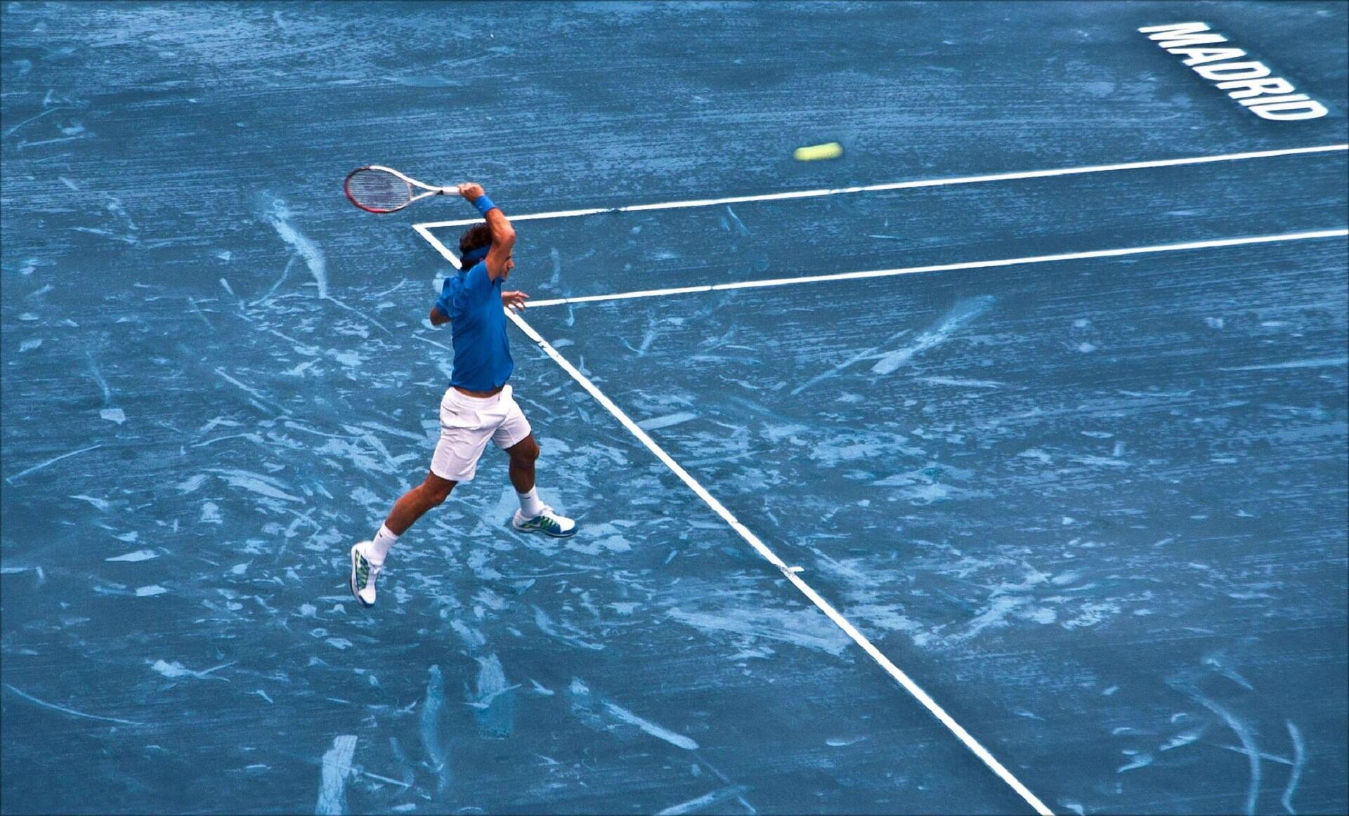 A tennis player on a blue tennis court. 