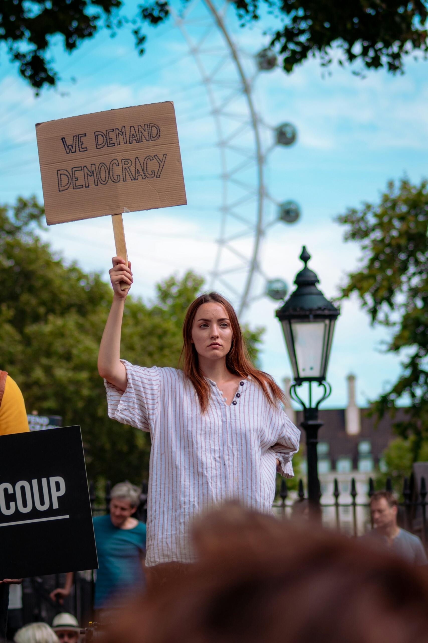 A woman holding up a sign on a cloudy day.