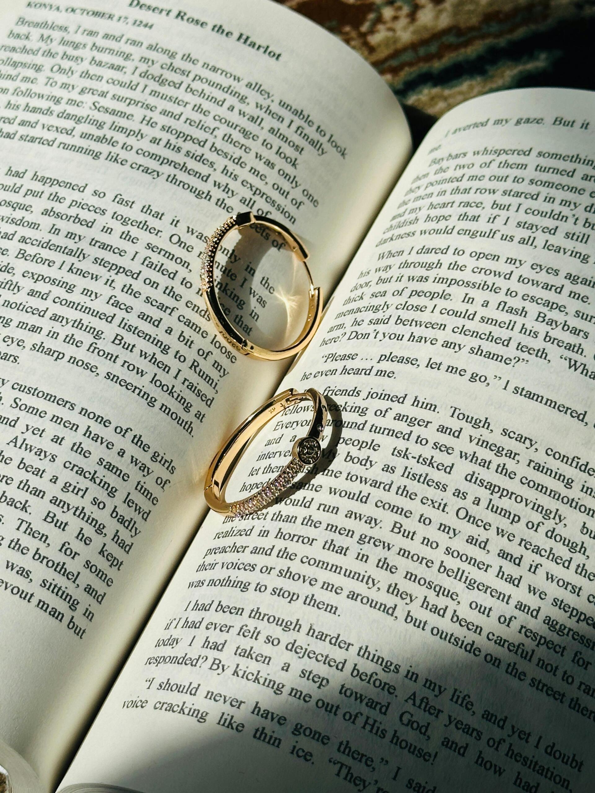 Elegant gold rings resting on the open pages of a book.