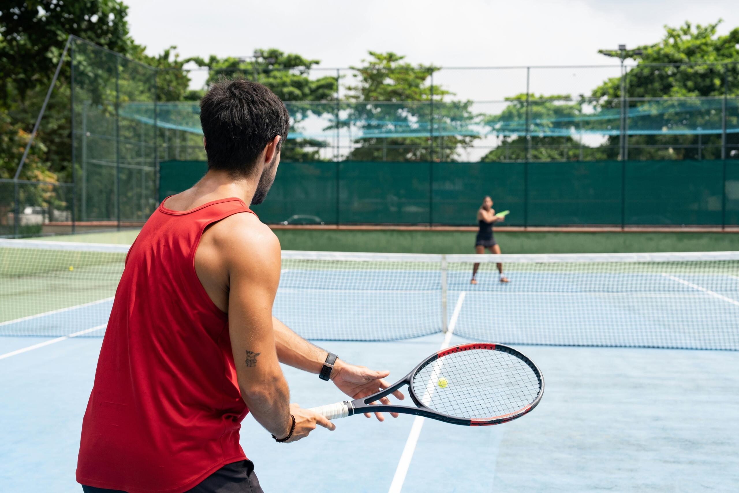 man playing tennis on a hard court