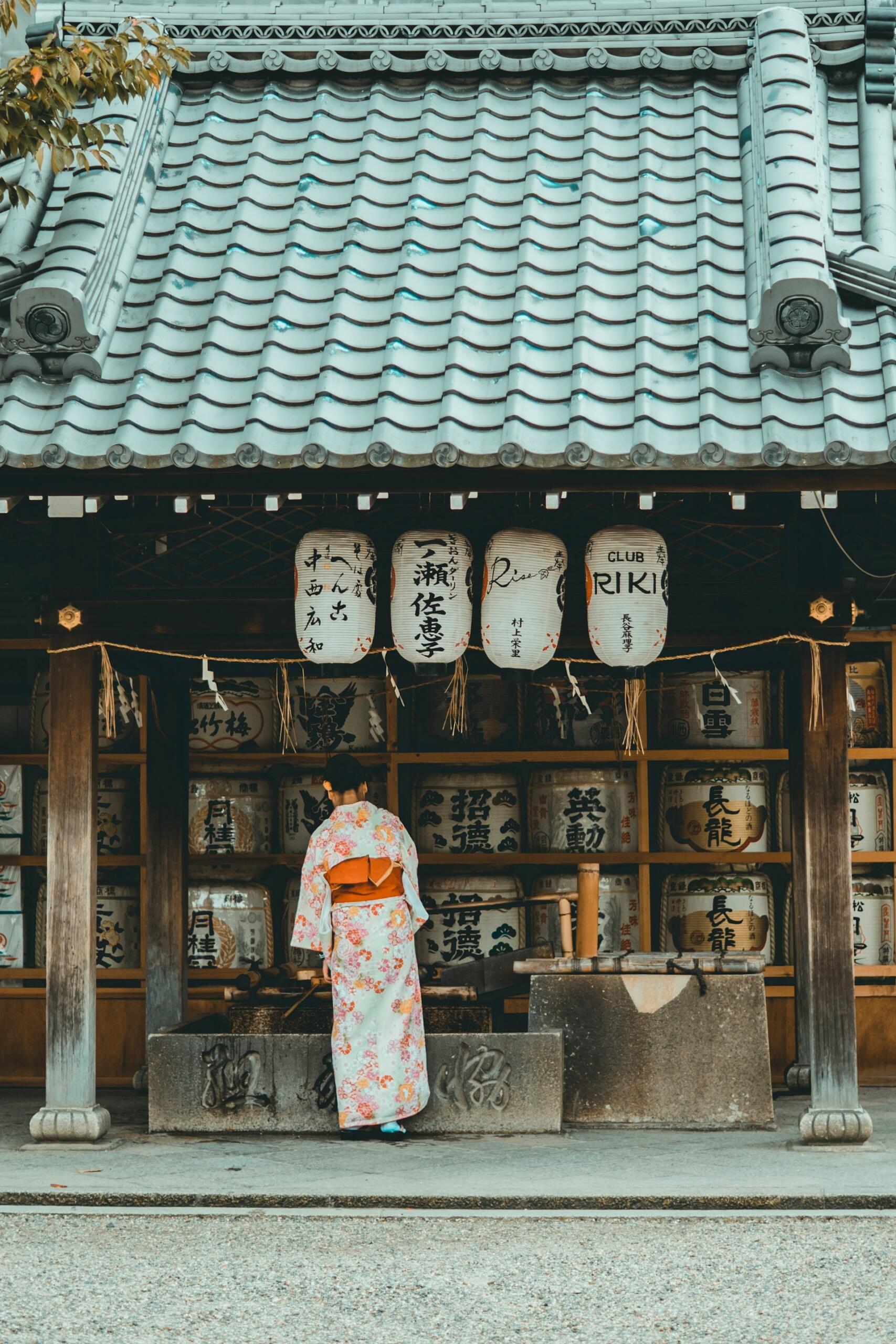 A woman in a kimono stands before a shop in Japan. 