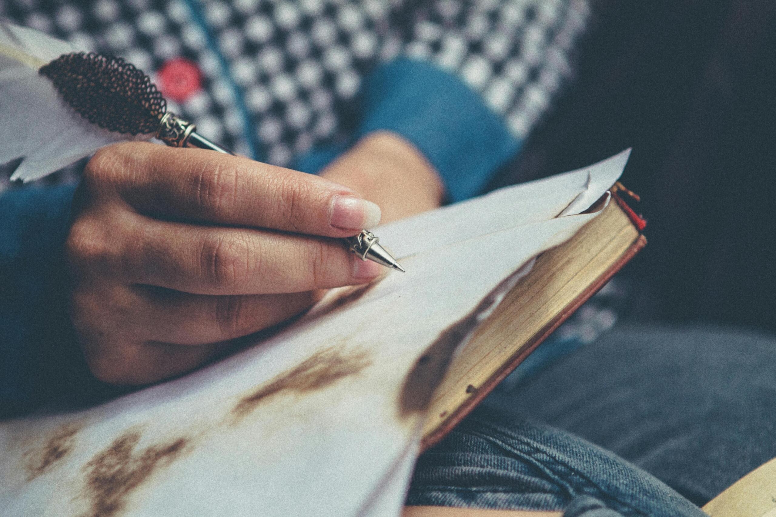A person writing on paper with a pen, focusing on their handwriting.