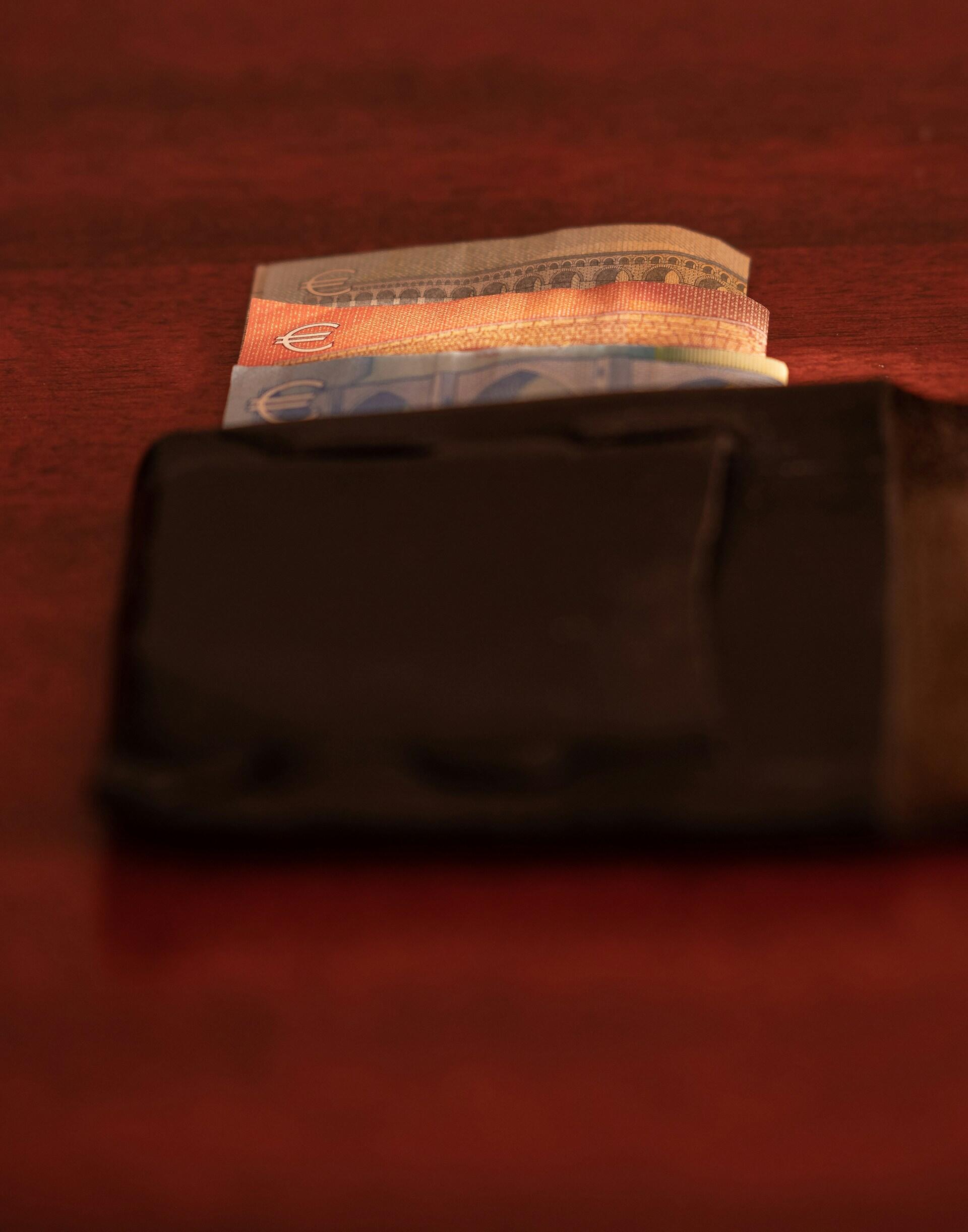 A brown wallet with Euro bills showing.