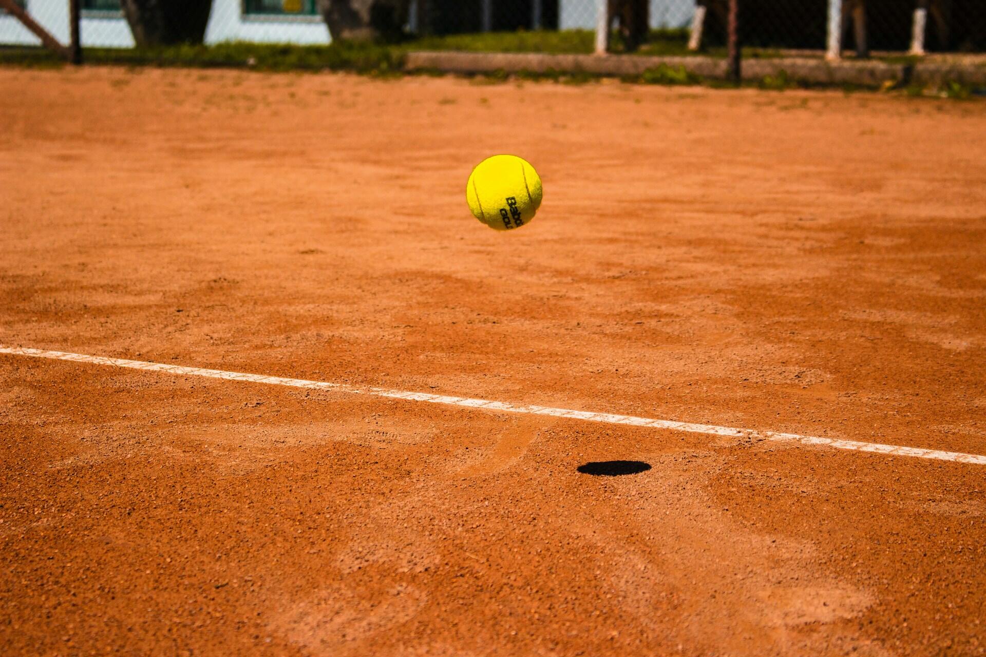 A tennis ball bouncing on a clay court.