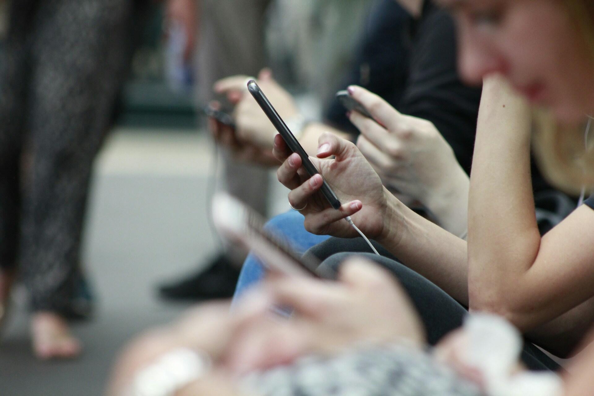 People holding smartphones, looking at the screens.
