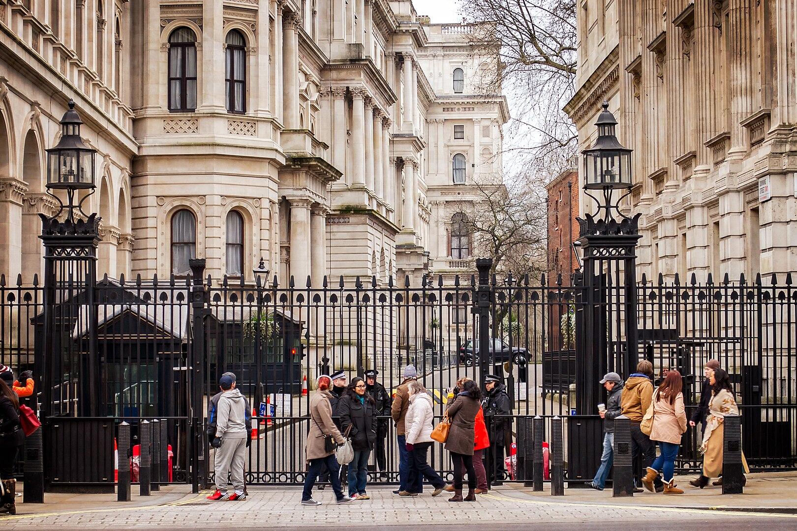People standing in front of a black gate on a cloudy day.