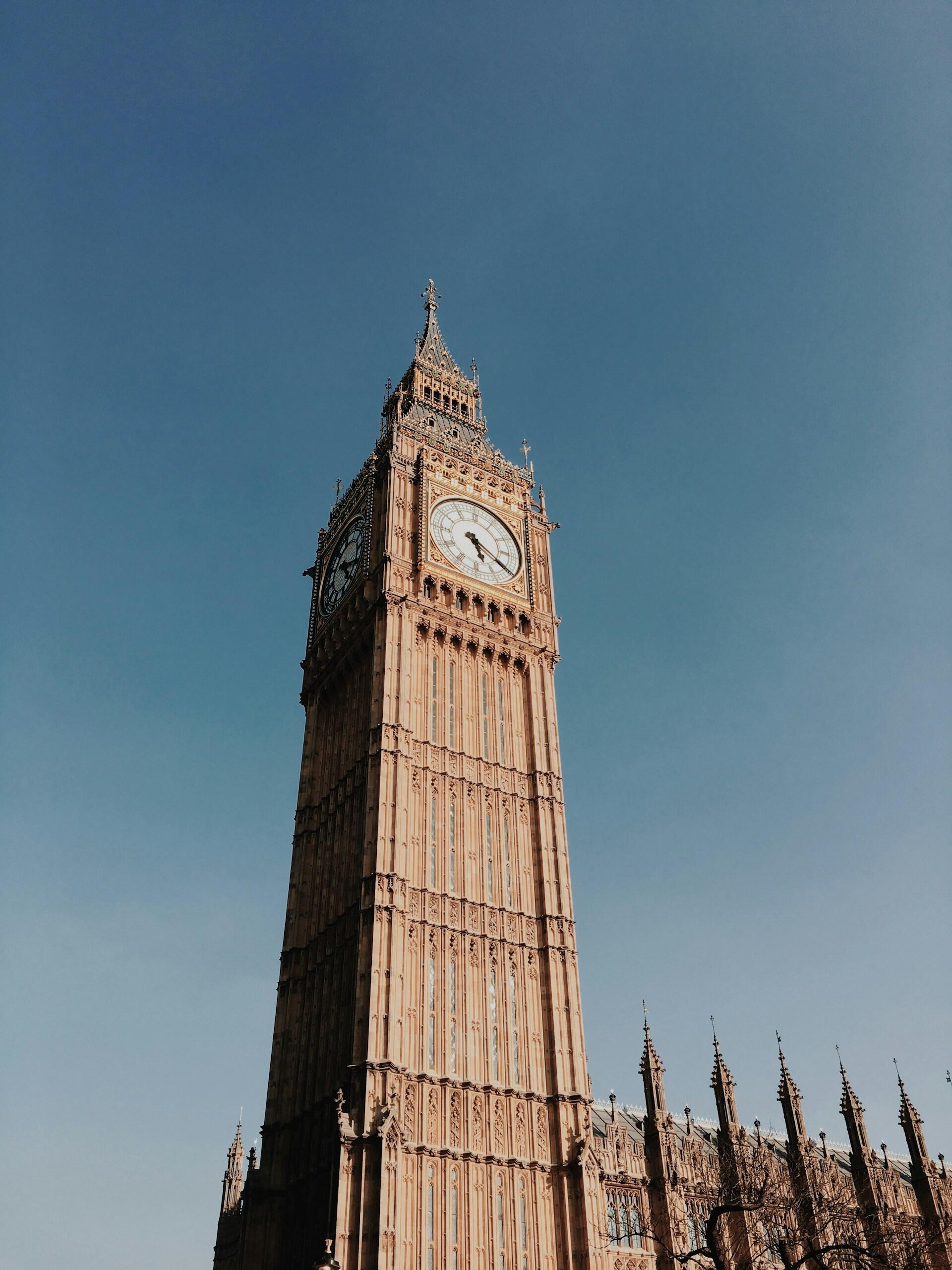 A tall stone tower with a clock on a sunny day.