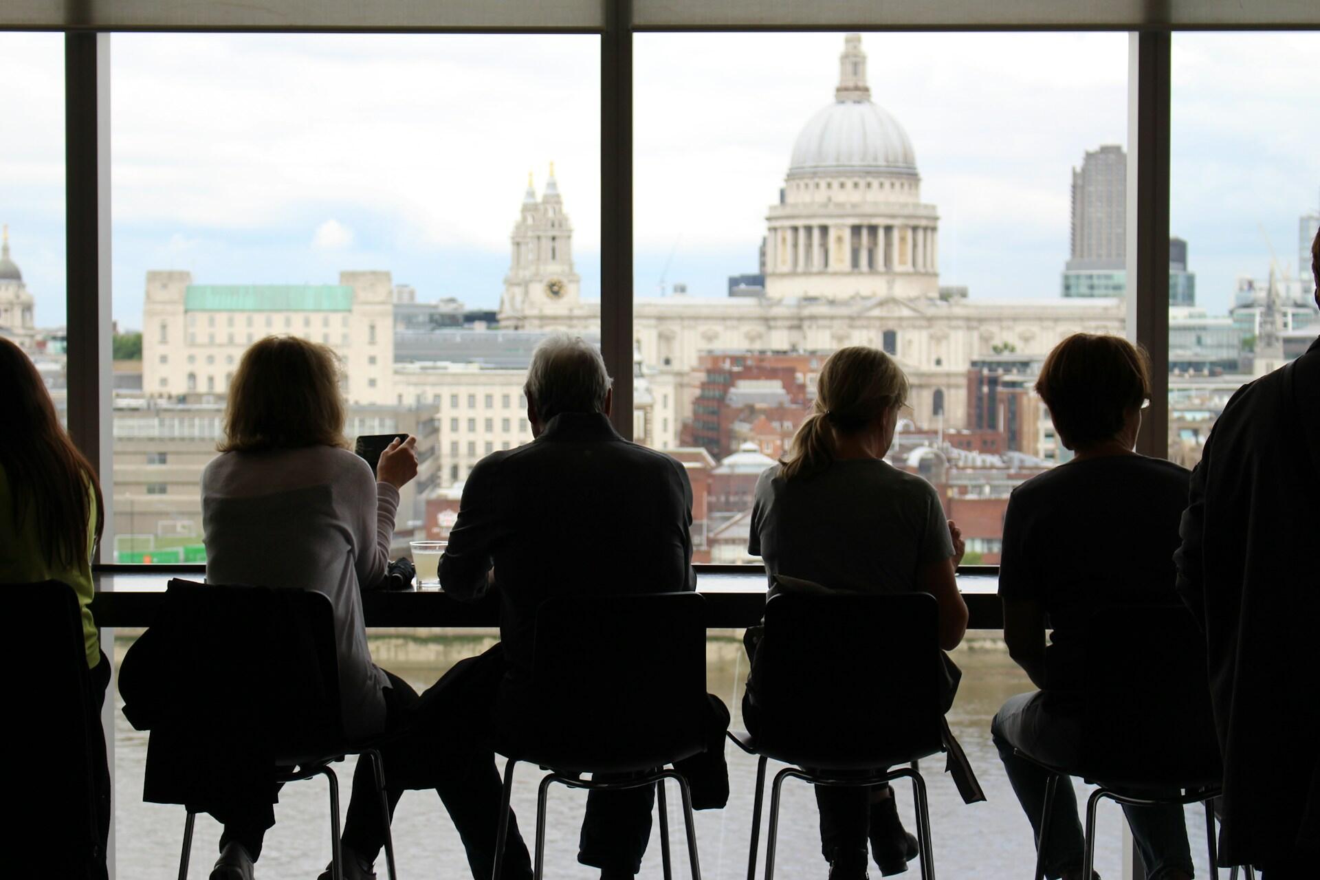 People in a café overlooking a cathedral in London.